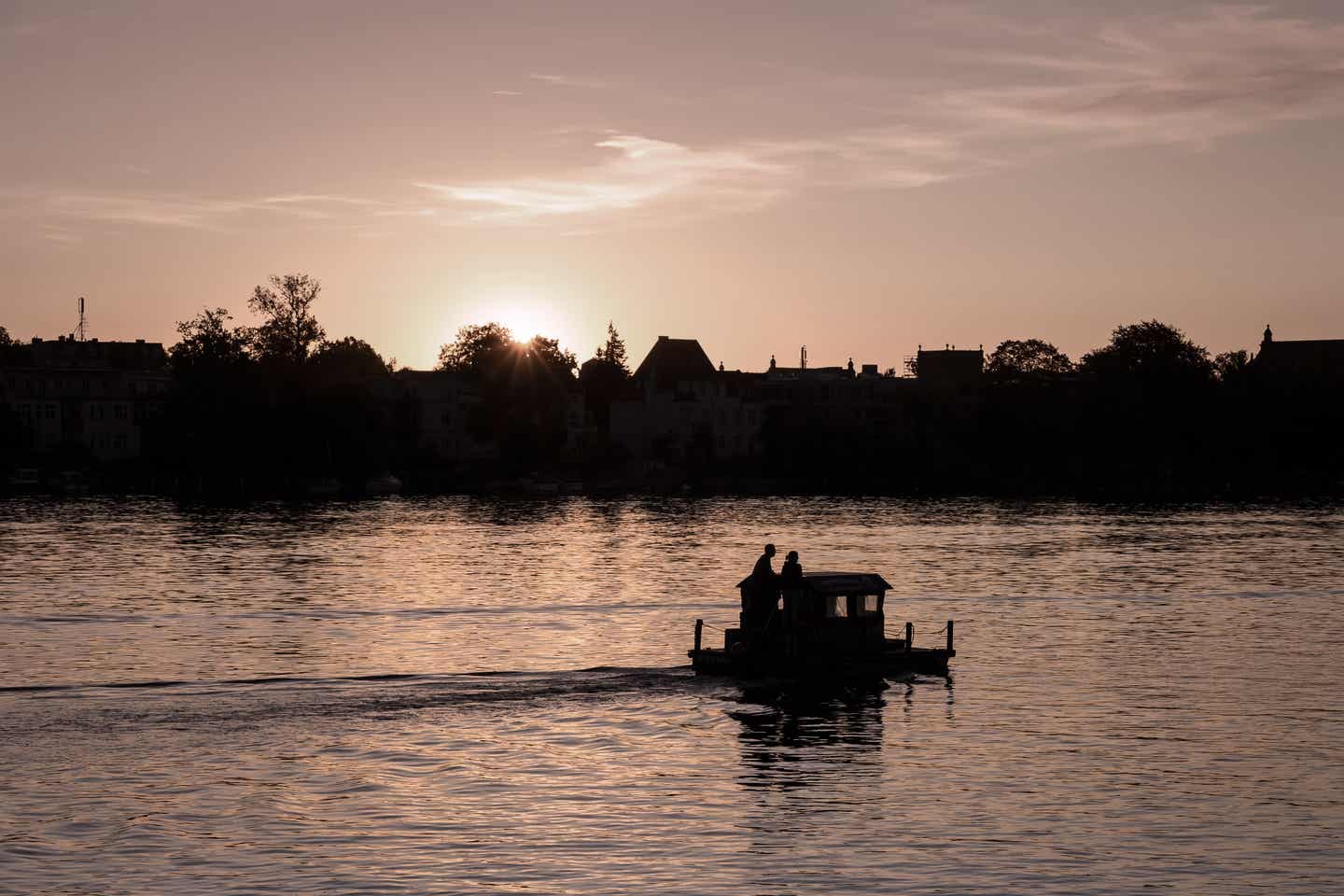 Brandenburg Urlaub mit DERTOUR. Paar mit kleinem Hausboot auf der Havel bei Sonnenuntergang