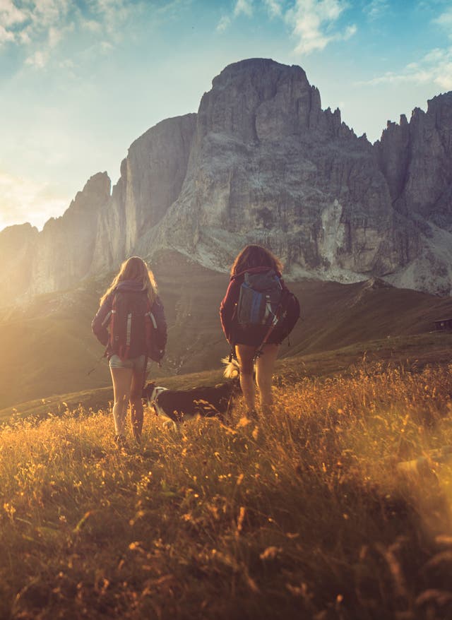 Hotel in Südtirol buchen Reisekalender September. Wanderer in Südtirol. Sonne strahlt über einem Berg