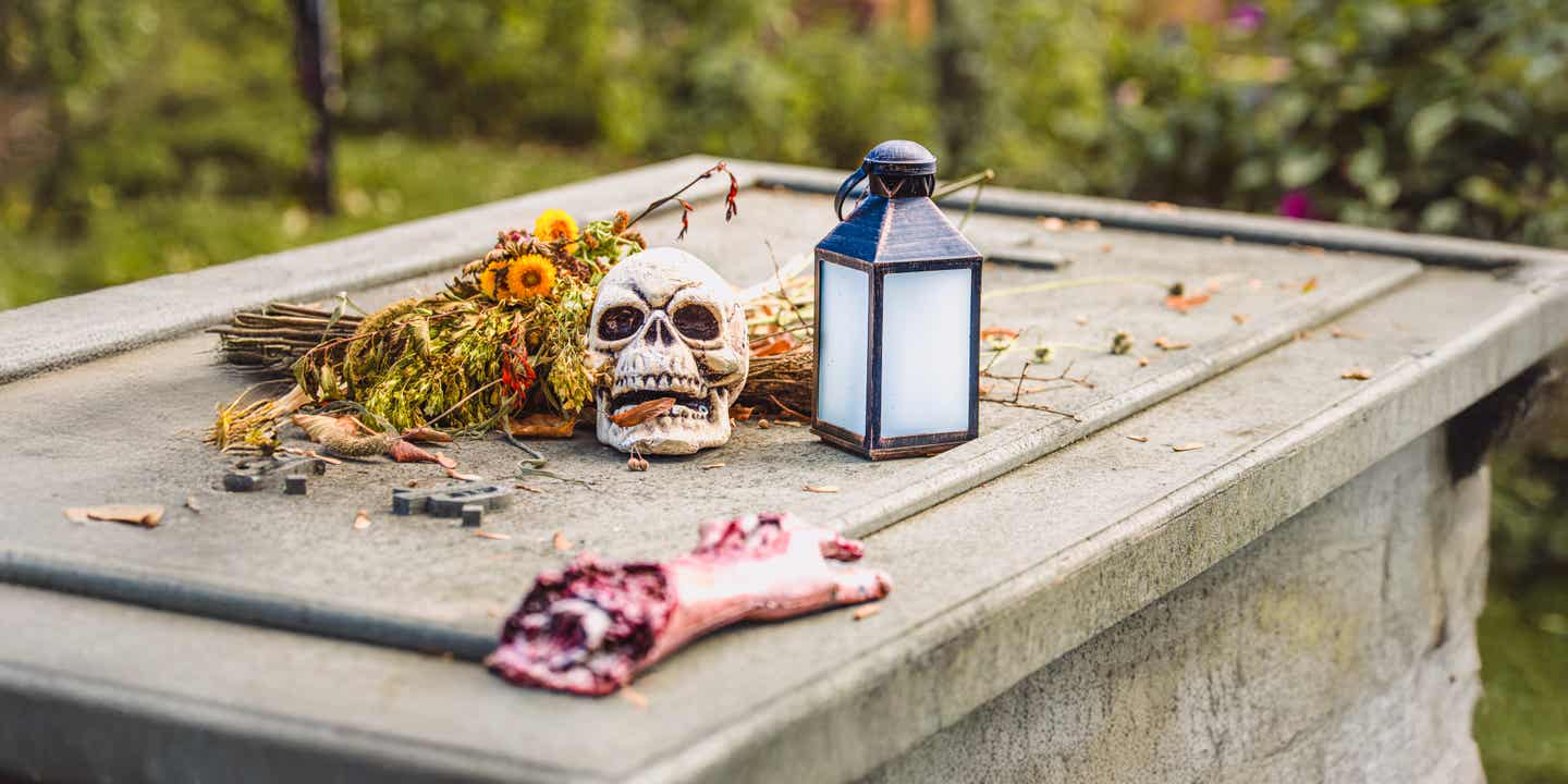 Eine abgetrennte Plastikhand sowie ein unechter Totenkopf auf einem Grab