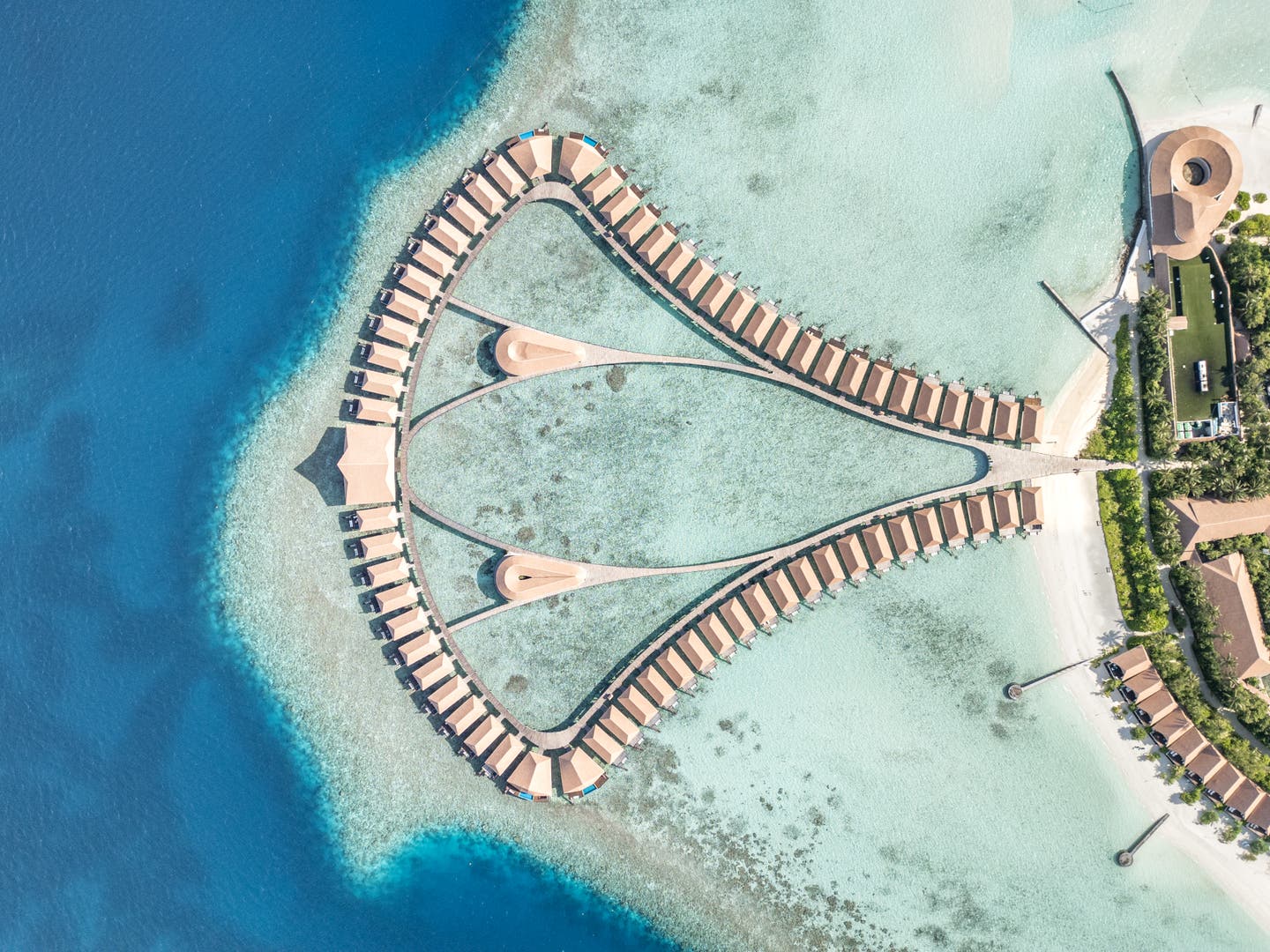 Topshot einer Drohne auf das Hotel und die Wasservillen im Ozean