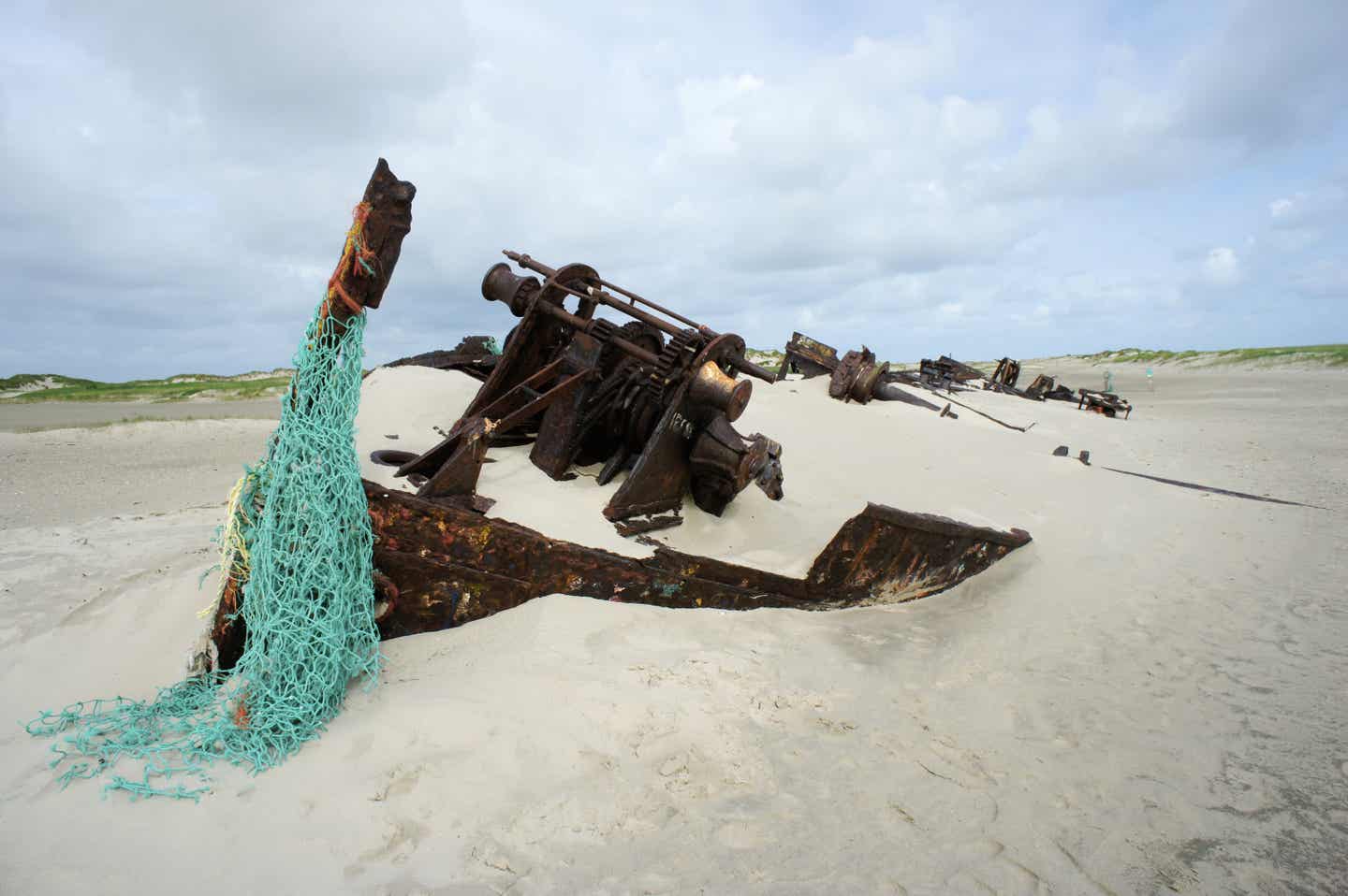 Norderney Urlaub mit DERTOUR. Detailaufnahme von Teilen eines Schiffswracks am Strand von Norderney