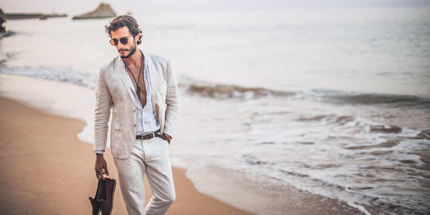 Mann im aufgelockteren Business-Anzug spaziert am Strand