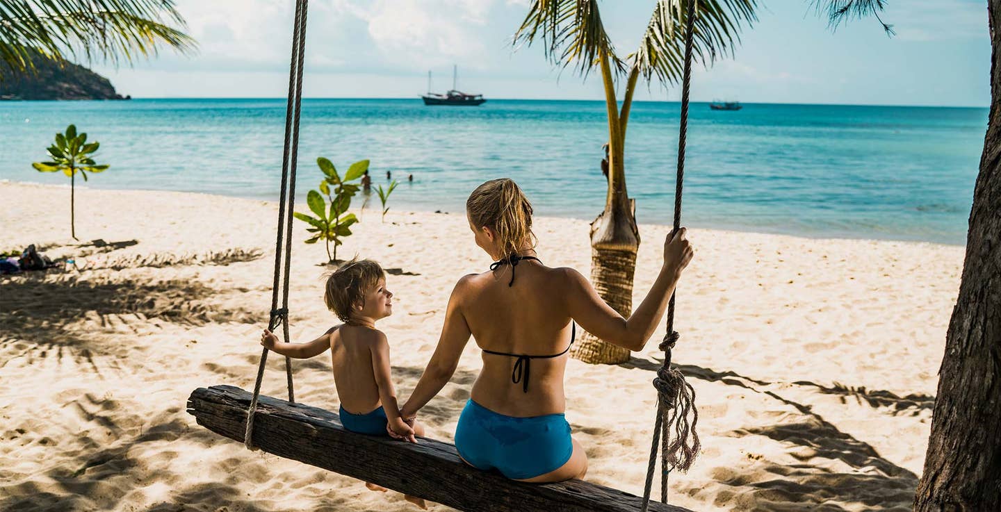 Mutter und Sohn sitzen auf einer Schaukel am Strand