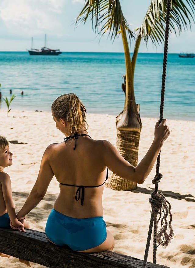 Familienurlaub Thailand Mutter und Sohn sitzen auf einer Schaukel am Strand