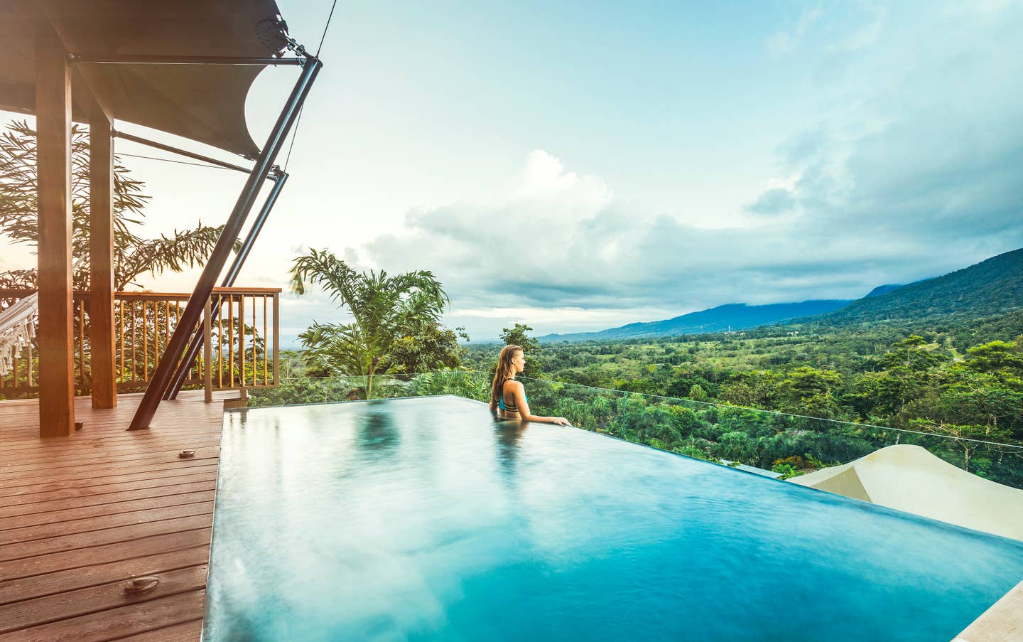 Eine Frau steht am Rande eines Infinitypools im Nyara Tented Camp auf Costa Rica und blickt über den Regenwald