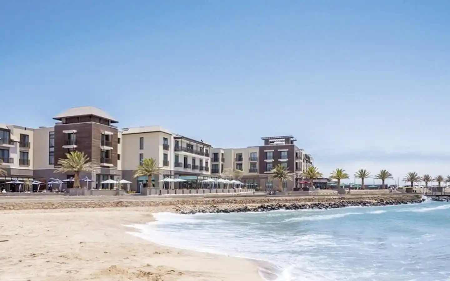 Außenansicht vom Strand Hotel Swakopmund in Namibia, direkt am Atlantik gelegen mit Promenade, Palmen und Sandstrand
