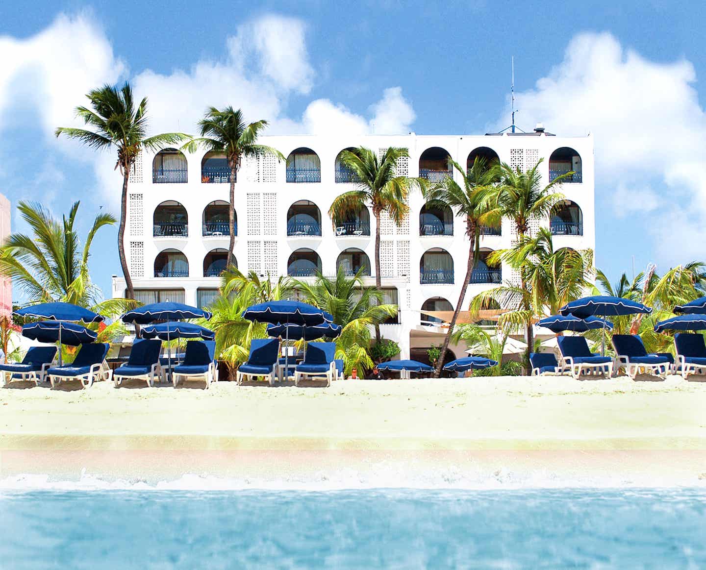 Weißes Hotelgebäude mit Balkonen, Palmen, direkte Strandlage