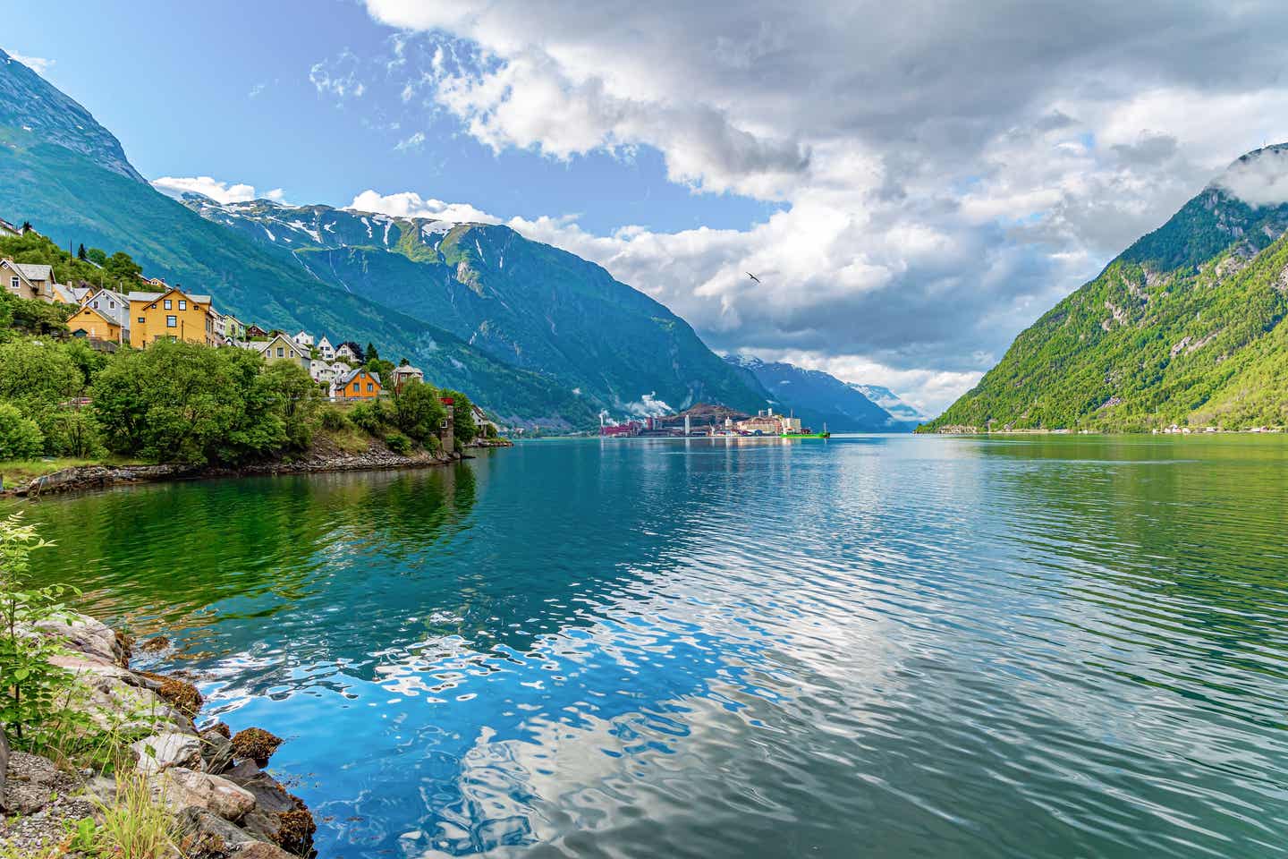 Hardangerfjord – Spektakulärer Fjord in Norwegen mit klarem Wasser, bunten Häusern, steilen grünen Bergen und bewölktem Himmel