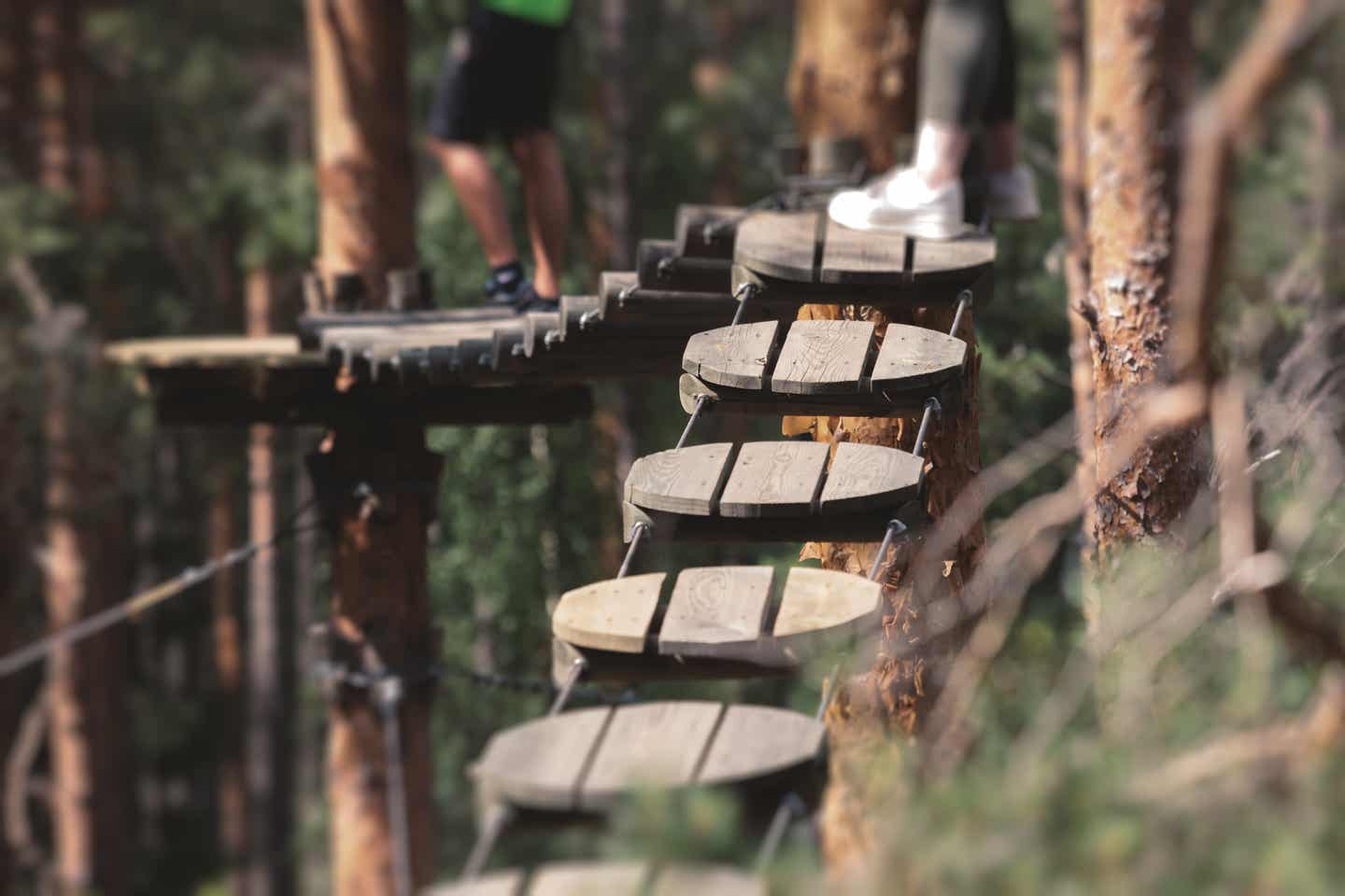 Hessen Urlaub mit DERTOUR. Beines eines Paares auf den Platten in einem Hochseilgarten im Wald