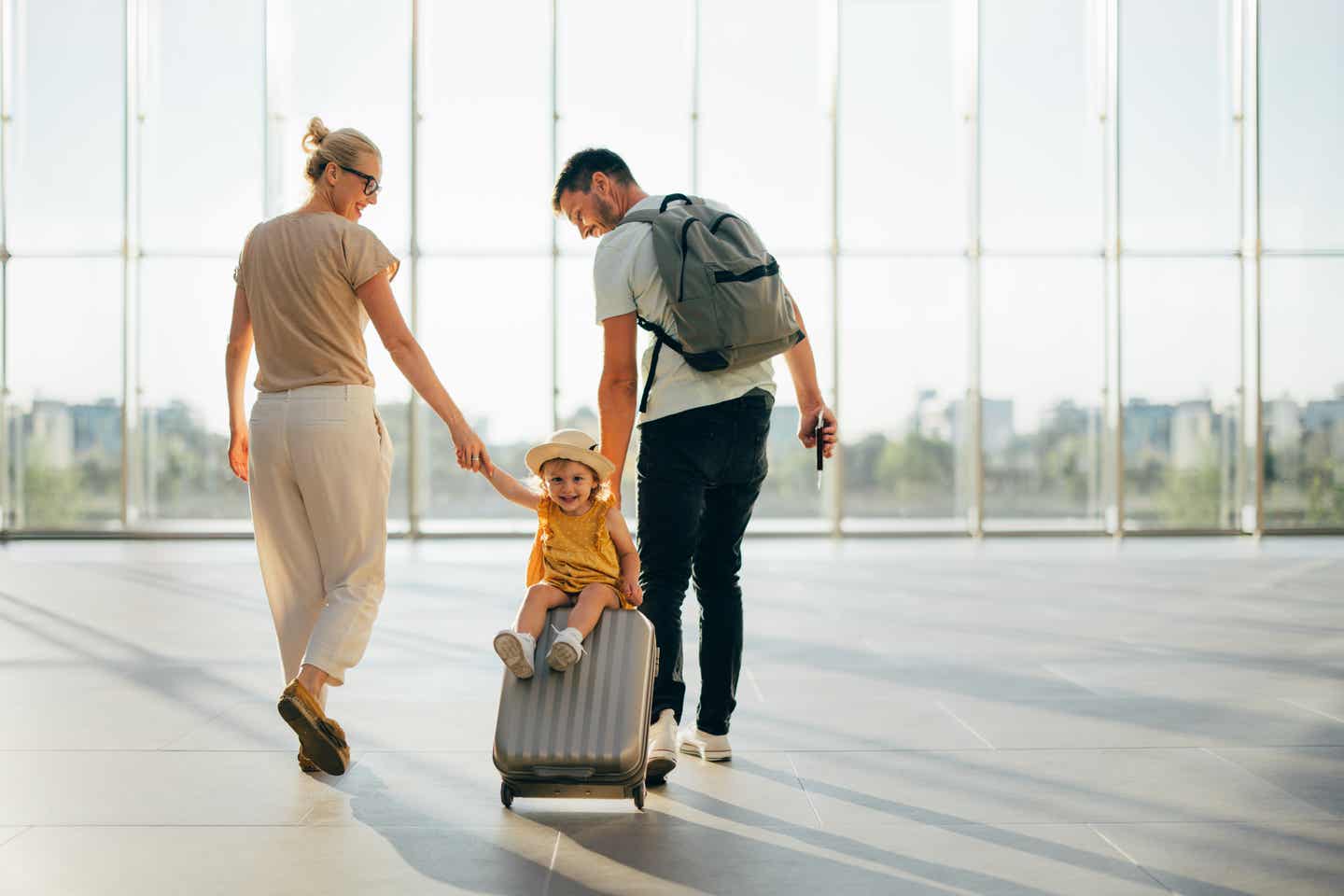 Packliste für Urlaub mit Kindern: Eine Familie mit Handgepäck am Flughafen