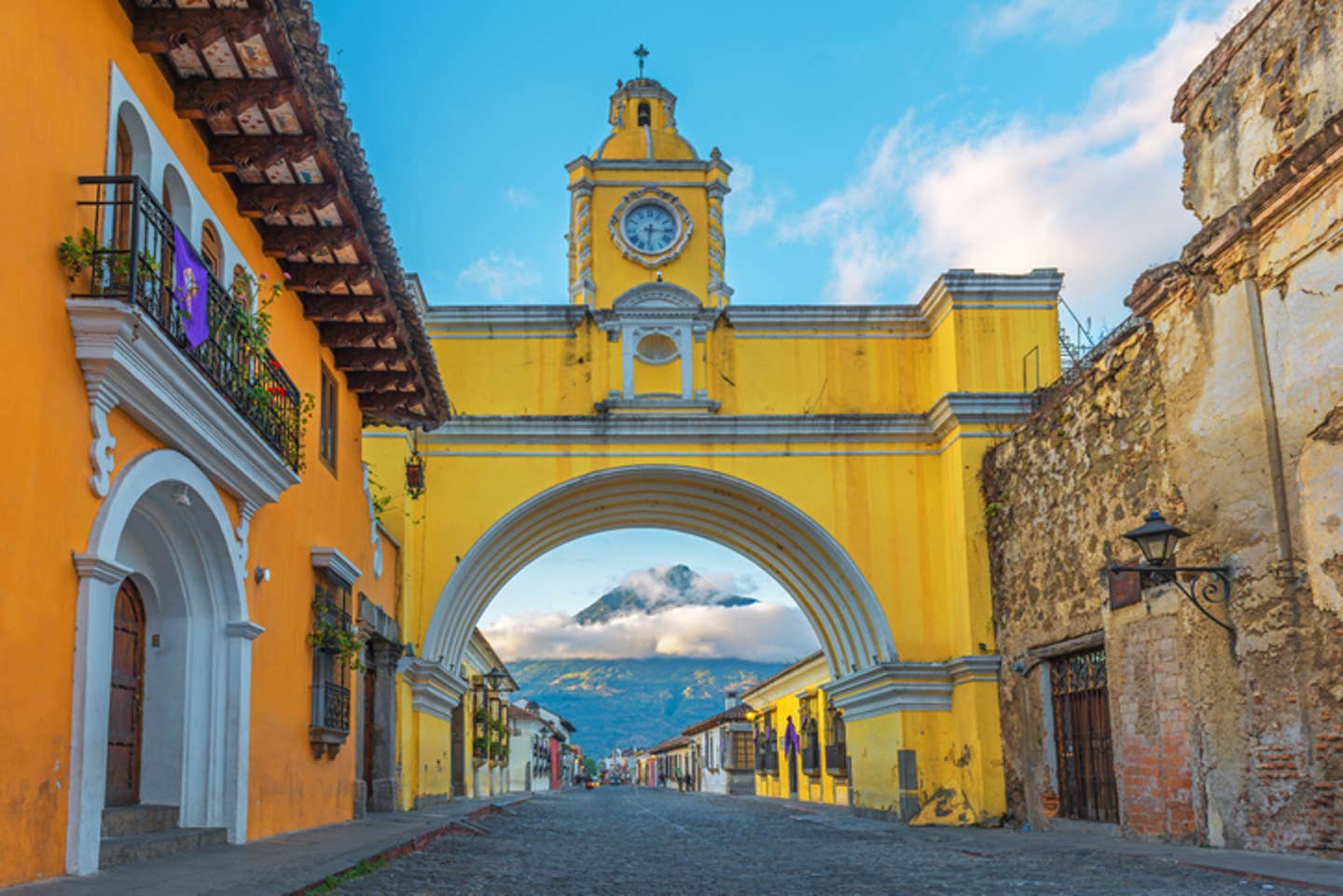 Rundreisen Guatemala: der gelbe Bogen in Antigua mit einem der Vulkane Guatemalas im Hintergrund