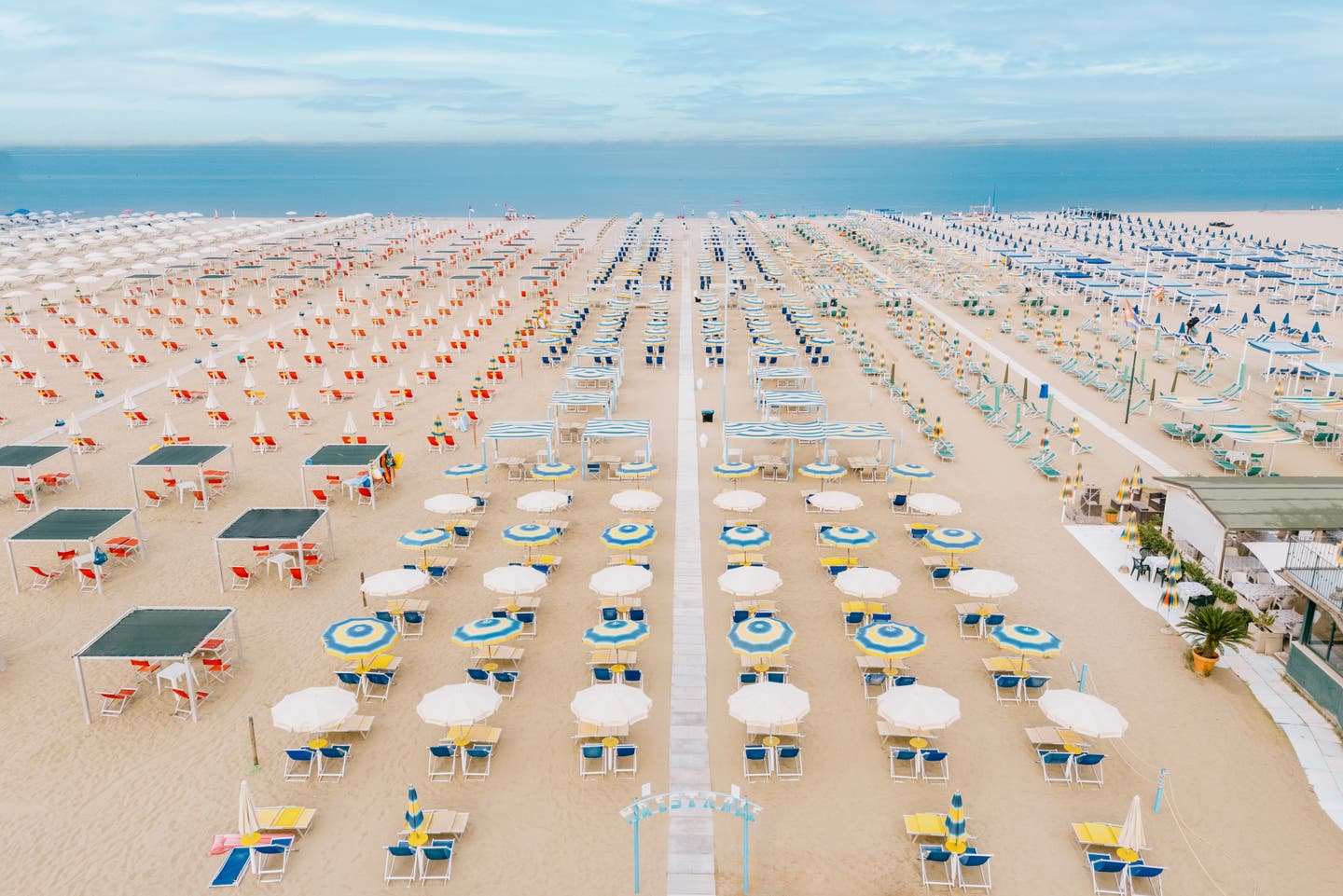 Breiter Strandabschnit mit zahlreichen Sonnenliegen und -schirmen