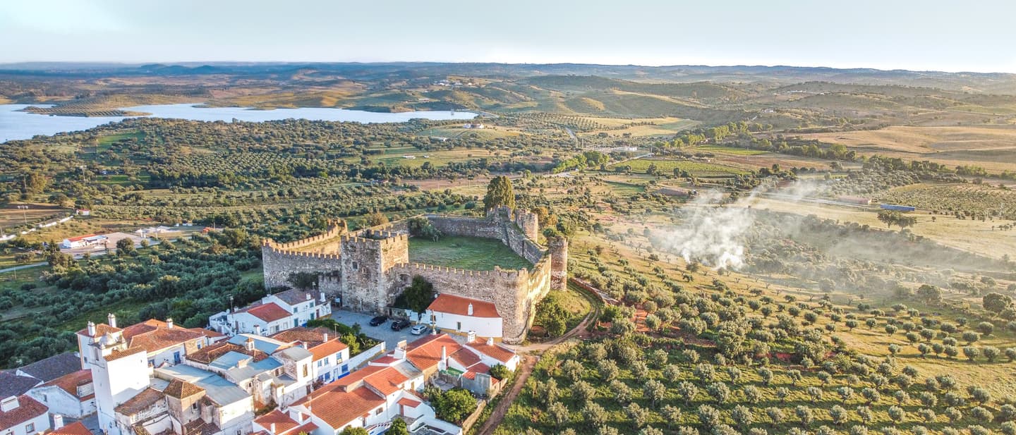 Luftaufnahme von Terena im Alentejo mit mittelalterlicher Burg, weißen Häusern und weiten Olivenhainen