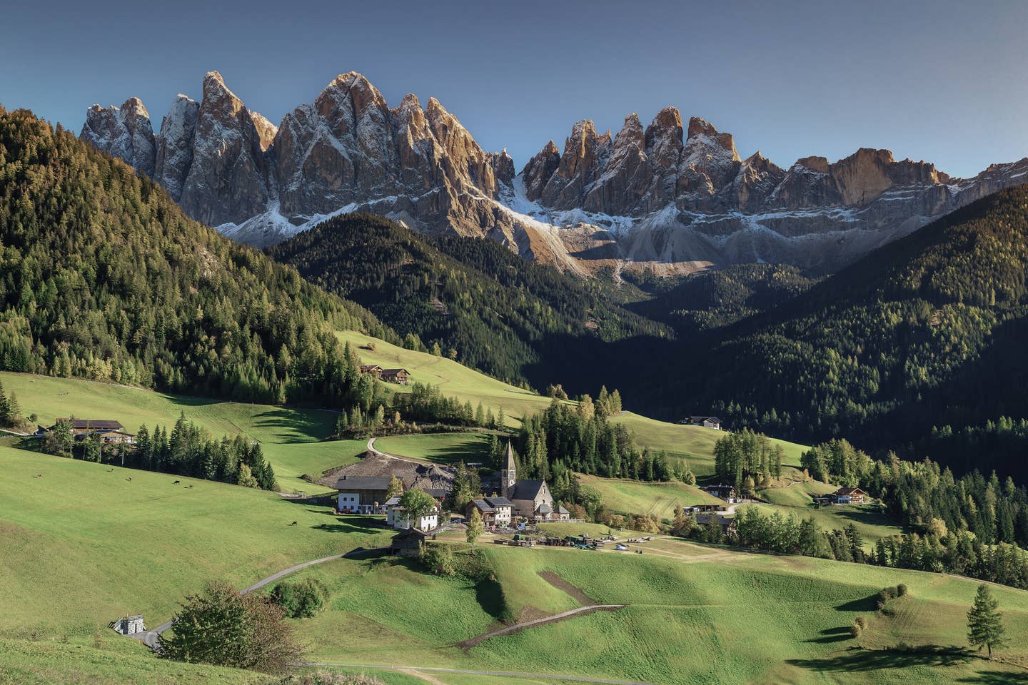 Dolomiten Urlaub mit DERTOUR. Panoramafoto des Dorfes Santa Maddalena mit den Dolomiten im Hintergrund