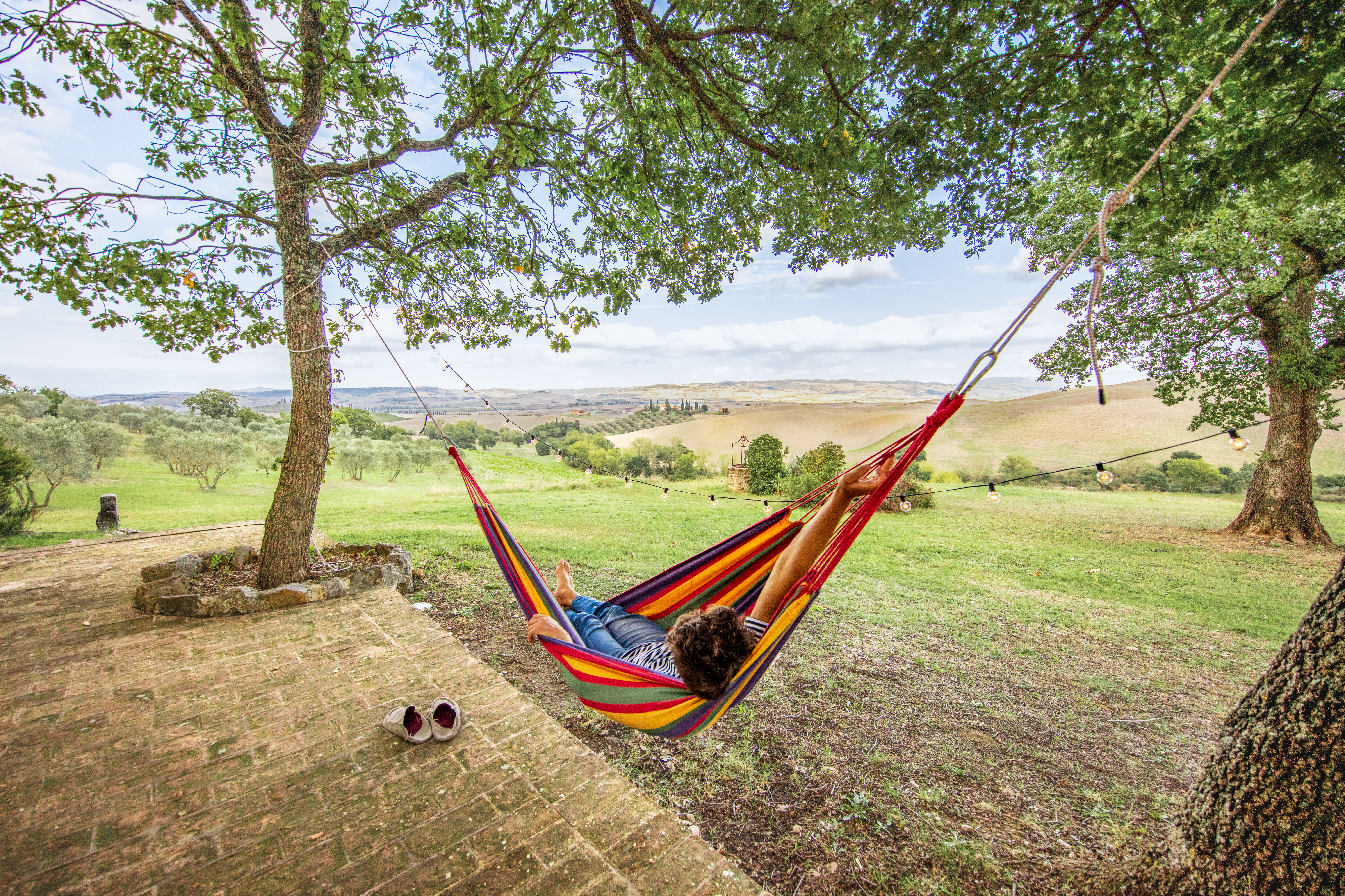 Person entspannt in einer Hängematte mit Blick auf die hügelige Landschaft der Toskana bei einem Landurlaub