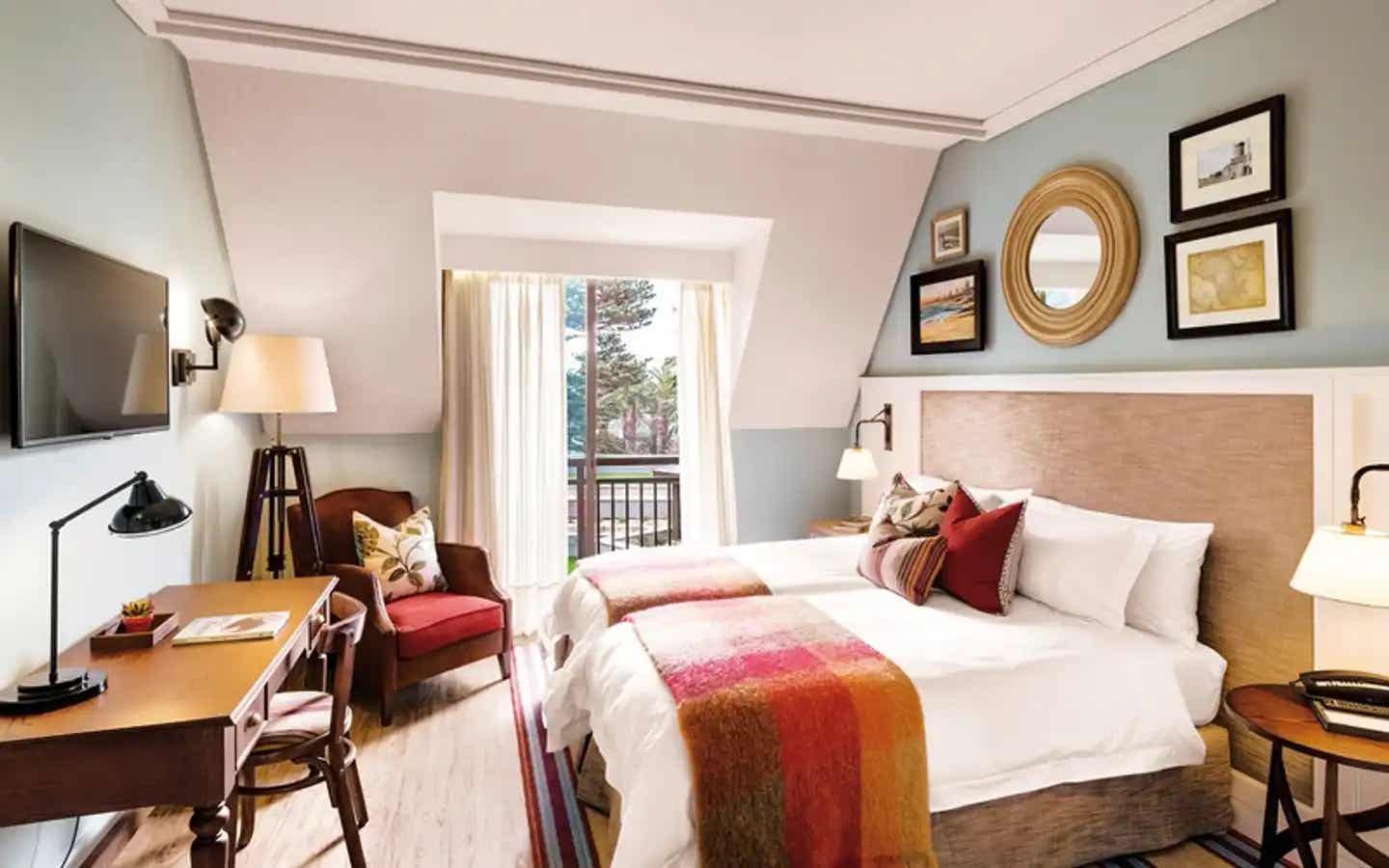 Gemütliches Zimmer im Strand Hotel in Swakopmund in Namibia mit zwei Betten, Schreibtisch, Sessel und stilvoller Dekoration Wohnen mit Charme – stilvolles Zimmer im Strand Hotel in Swakopmund