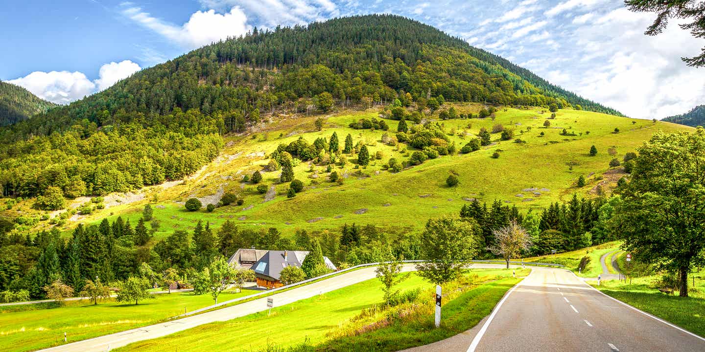 Deutschland-Roadtrip auf einer Straße im Schwarzwald, die von grünen Hügelketten gesäumt wird