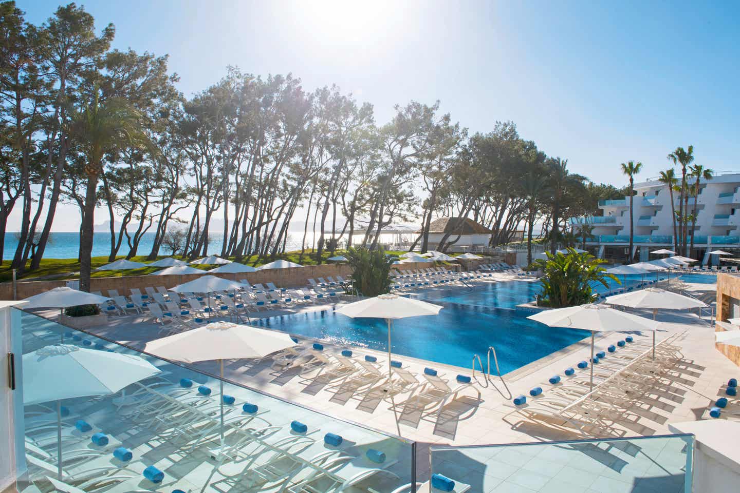 Beste Familienhotels Mallorca – Poolbereich des Iberostar Selection Playa de Muro Village mit Liegen, Sonnenschirmen und direktem Blick auf das Meer