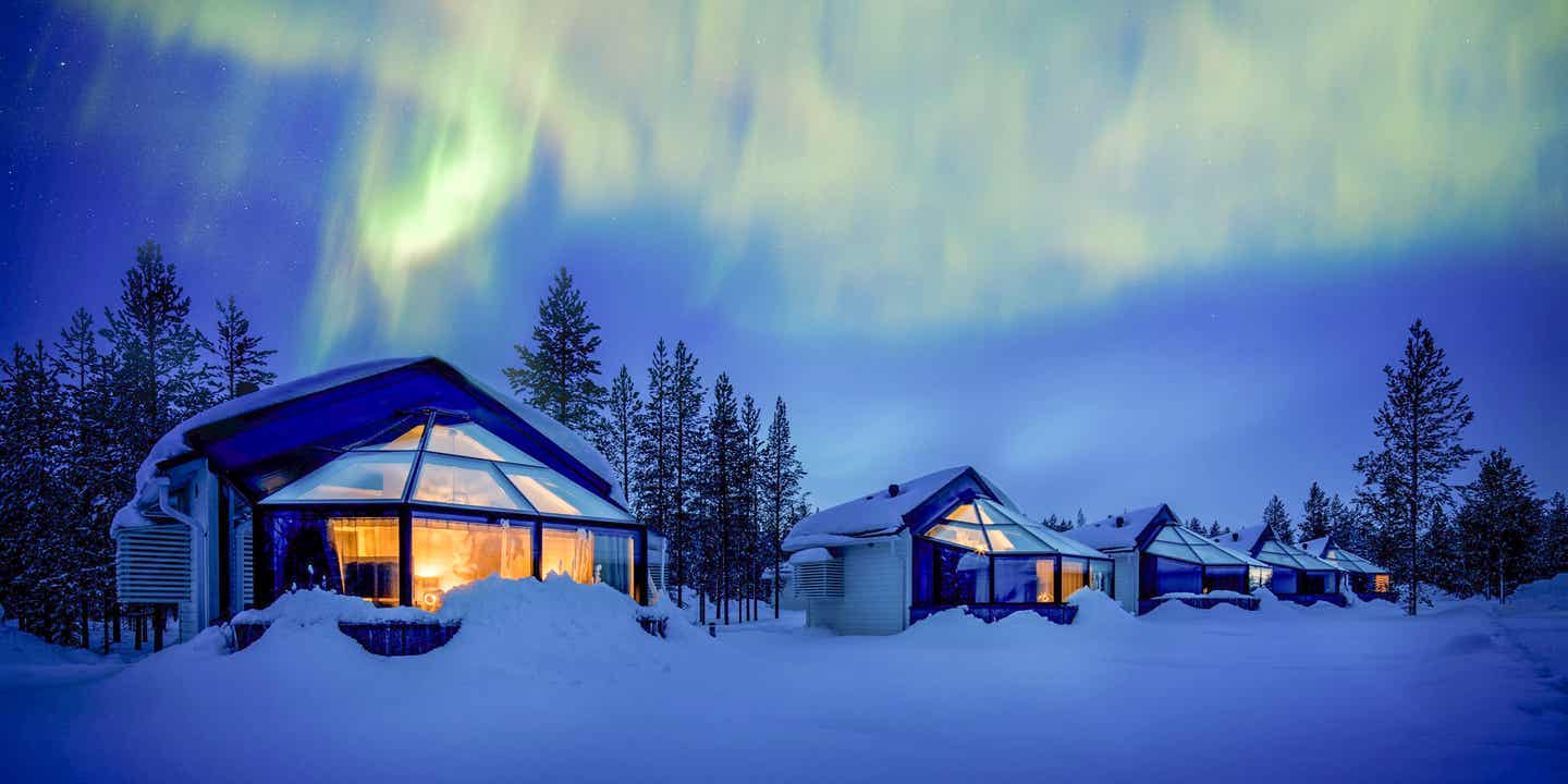 Blick auf Glas-Iglus des Hotels Santas Igloss Arctic Circle im Schnee mit Polarlichtern