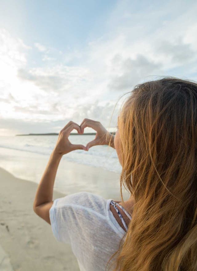 Partner Frau am Strand zeigt Herz