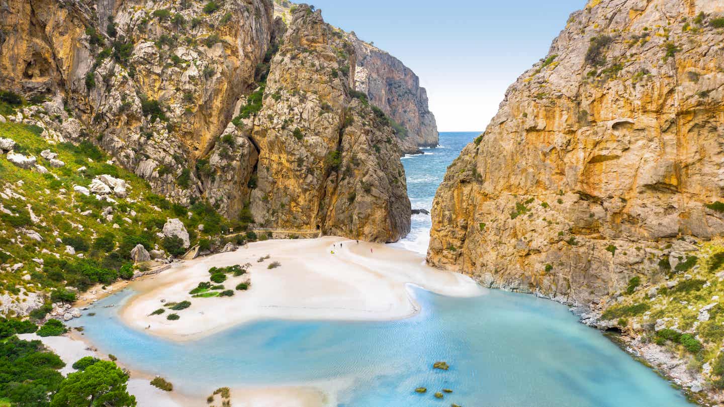 Blick auf den Torrente de Pareis auf Mallorca, der von zwei Felsen eingerahmt wird und im Hintergrund das blaue Meer zeigt