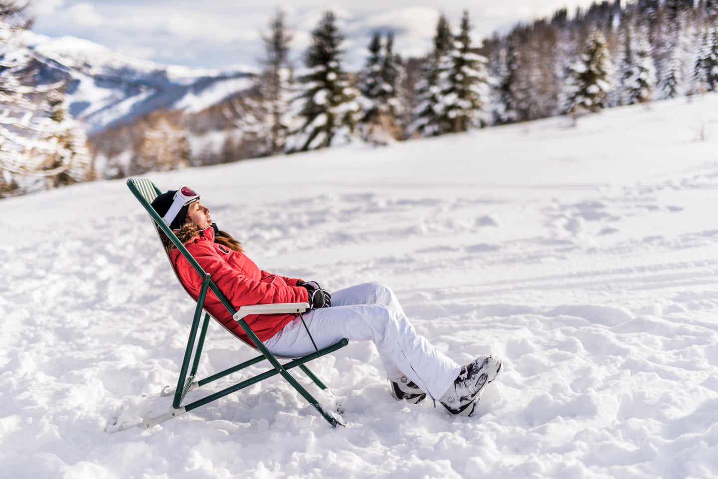 Eine Skifahrerin entspannt in einem Liegestuhl auf der Piste