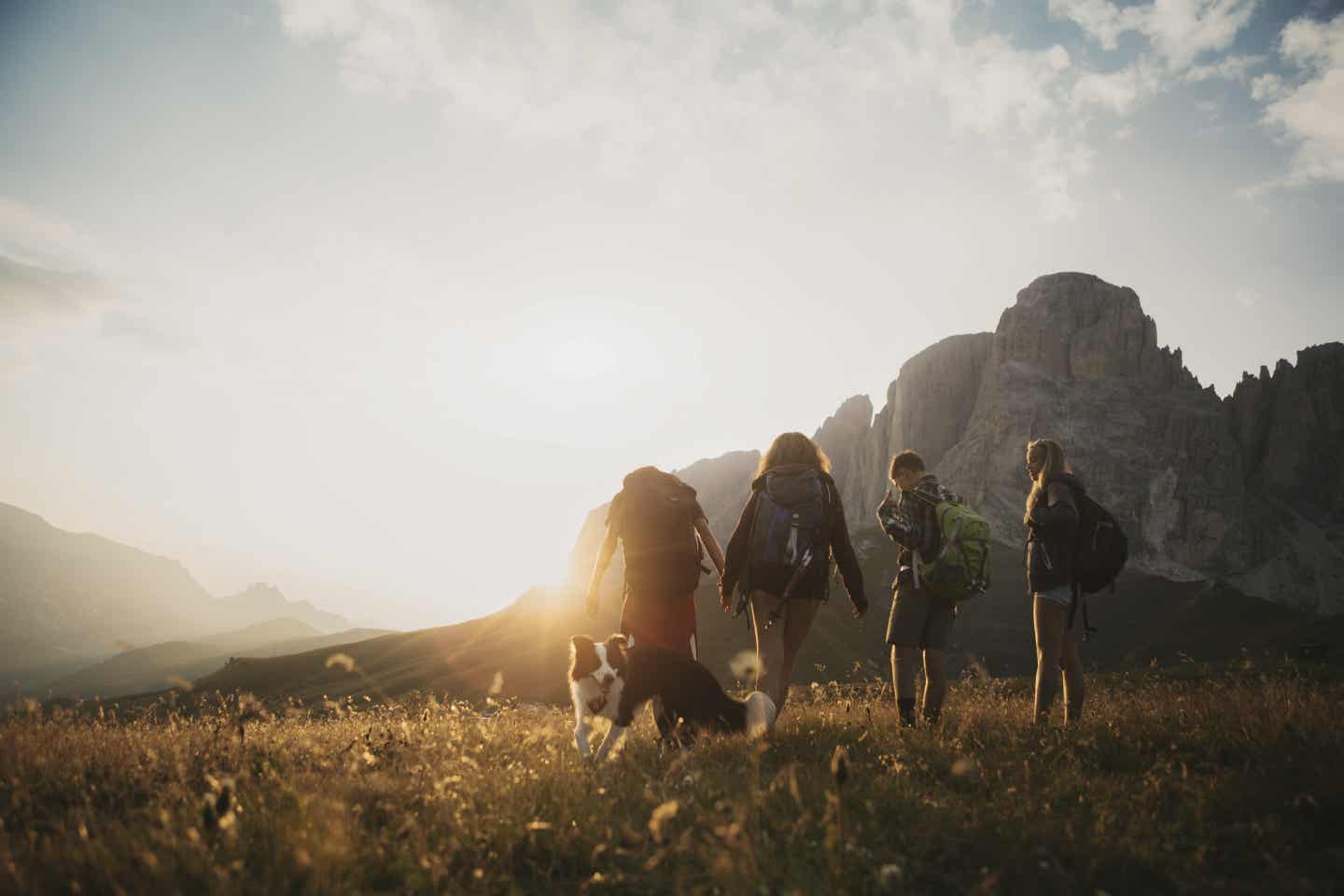 Dolomiten Urlaub mit DETOUR. Familie wandert mit Hund durch die Dolomiten kurz nach Sonnenaufgang