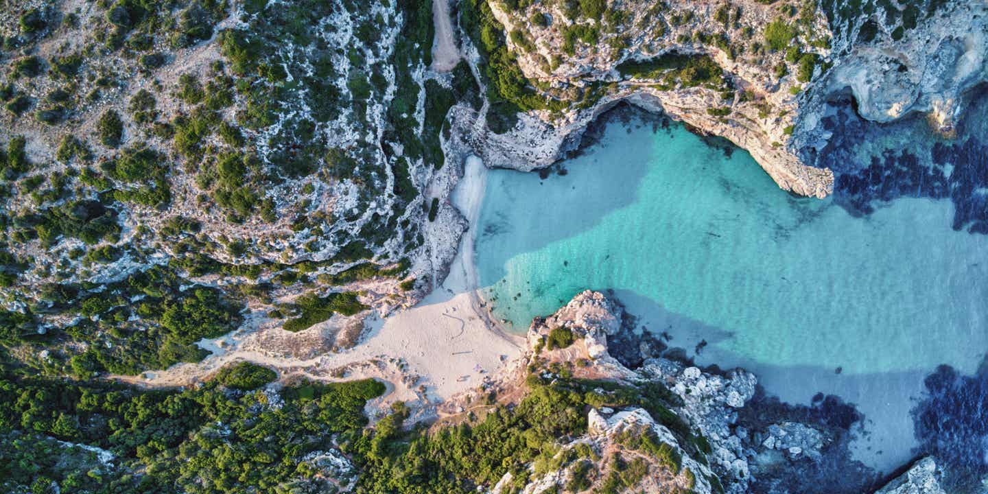 Luftaufnahme der Marmorbucht auf Mallorca mit kristallklarem türkisfarbenem Wasser und umgeben von steilen Felsen – ein verstecktes Paradies und Highlight unter den Mallorca-Sehenswürdigkeiten