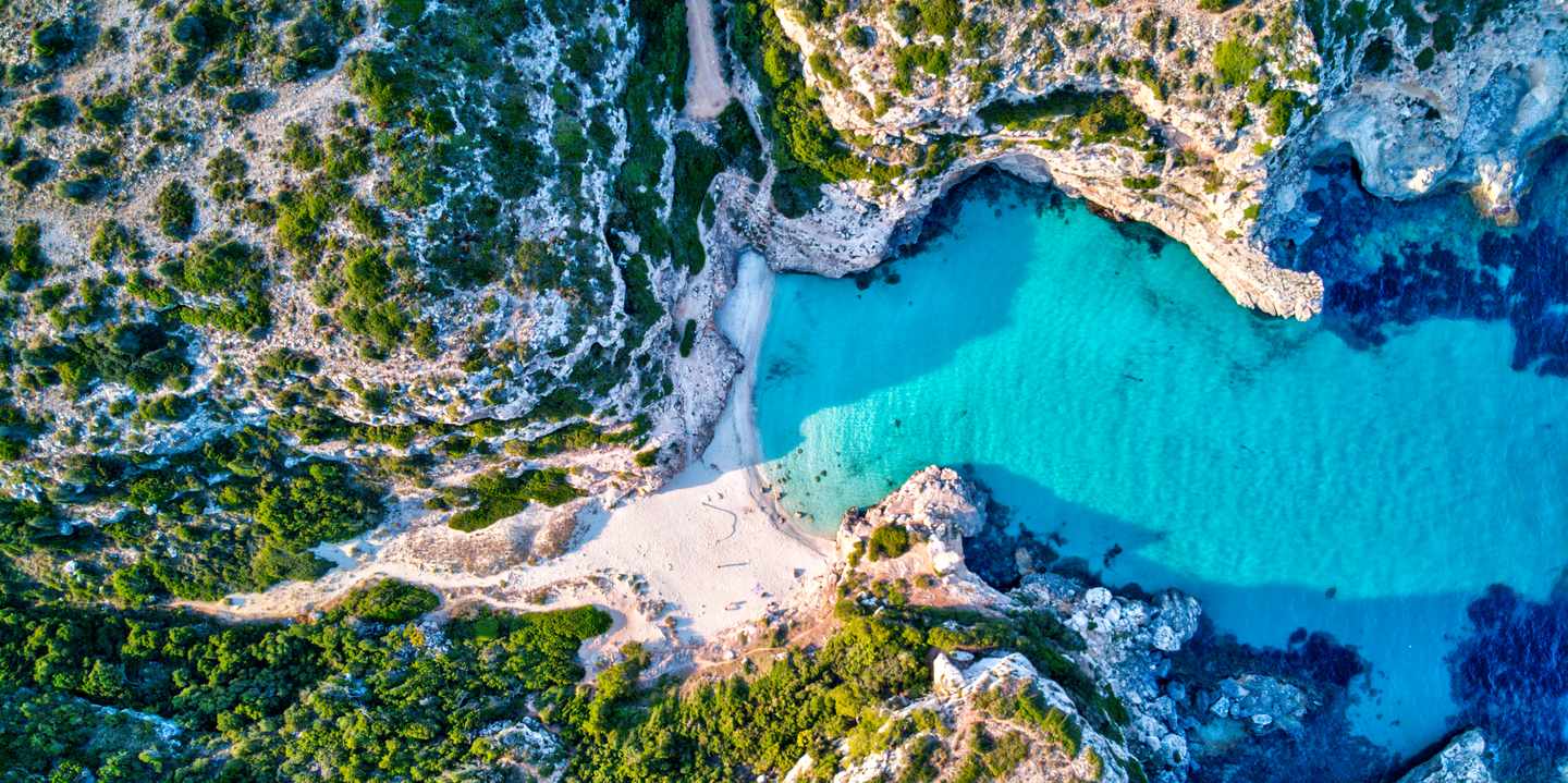Cala Marmols auf Mallorca aus der Luft mit heller Sandbucht, türkisfarbenem Wasser und umgebenden Felsklippen
