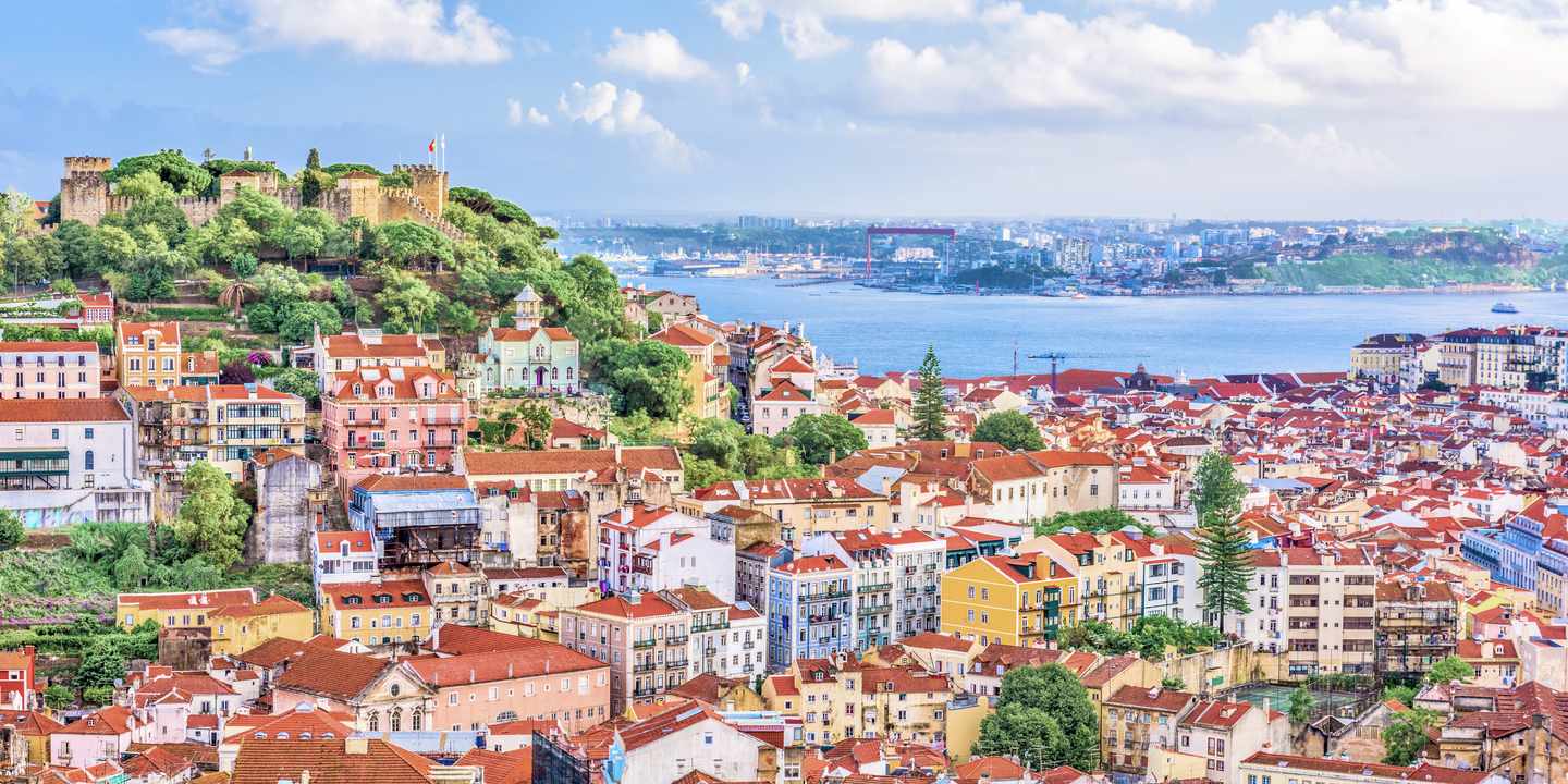Blick auf Lissabon mit bunten Häusern, dem Castelo de Sao Jorge und dem Tejo im Hintergrund
