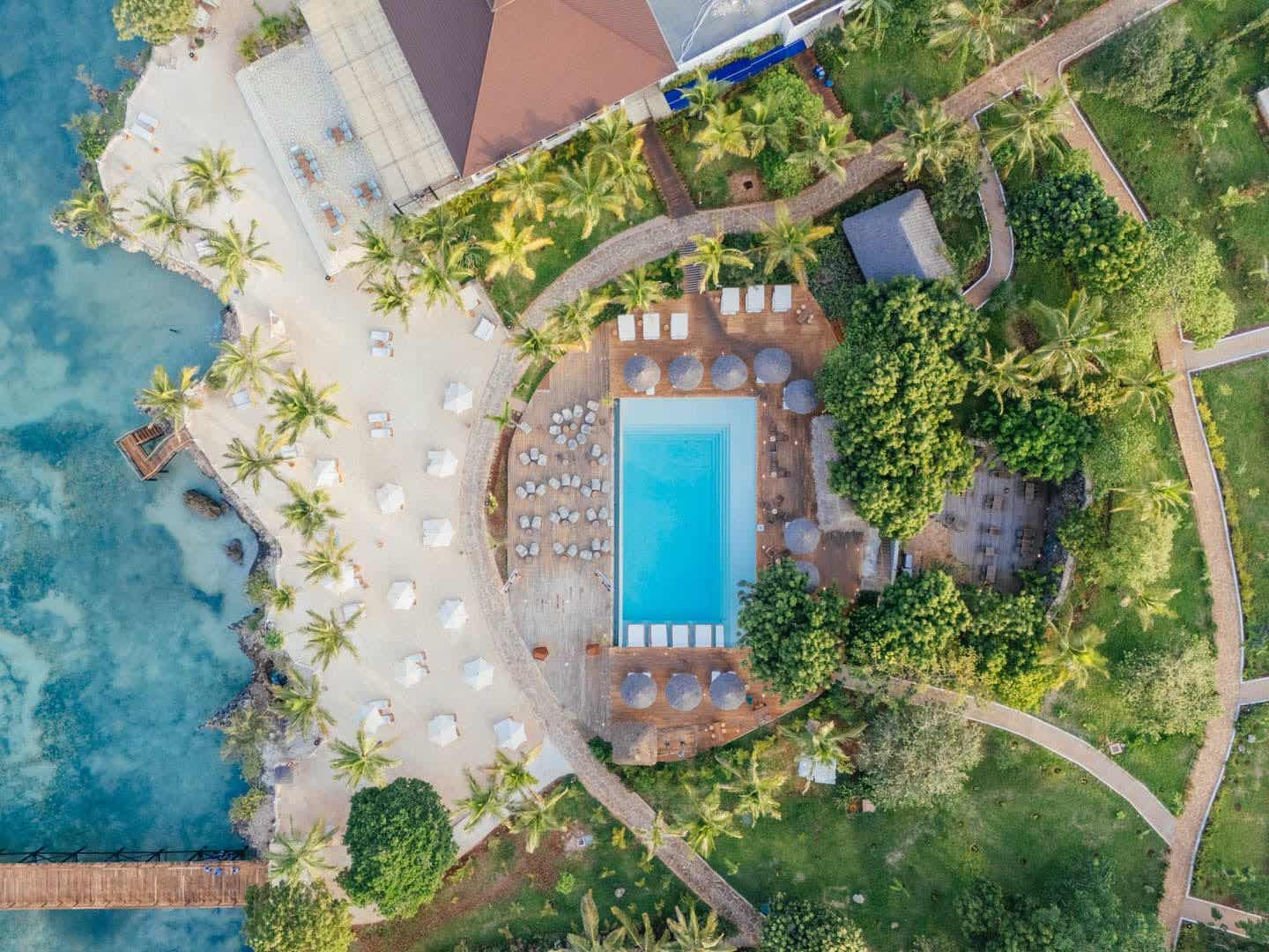 Luftaufnahme des Pools im Aldiana Club Zanzibar Kwanza in Kizimkazi, Sansibar – umgeben von Palmen, Liegen und Sonnenschirmen