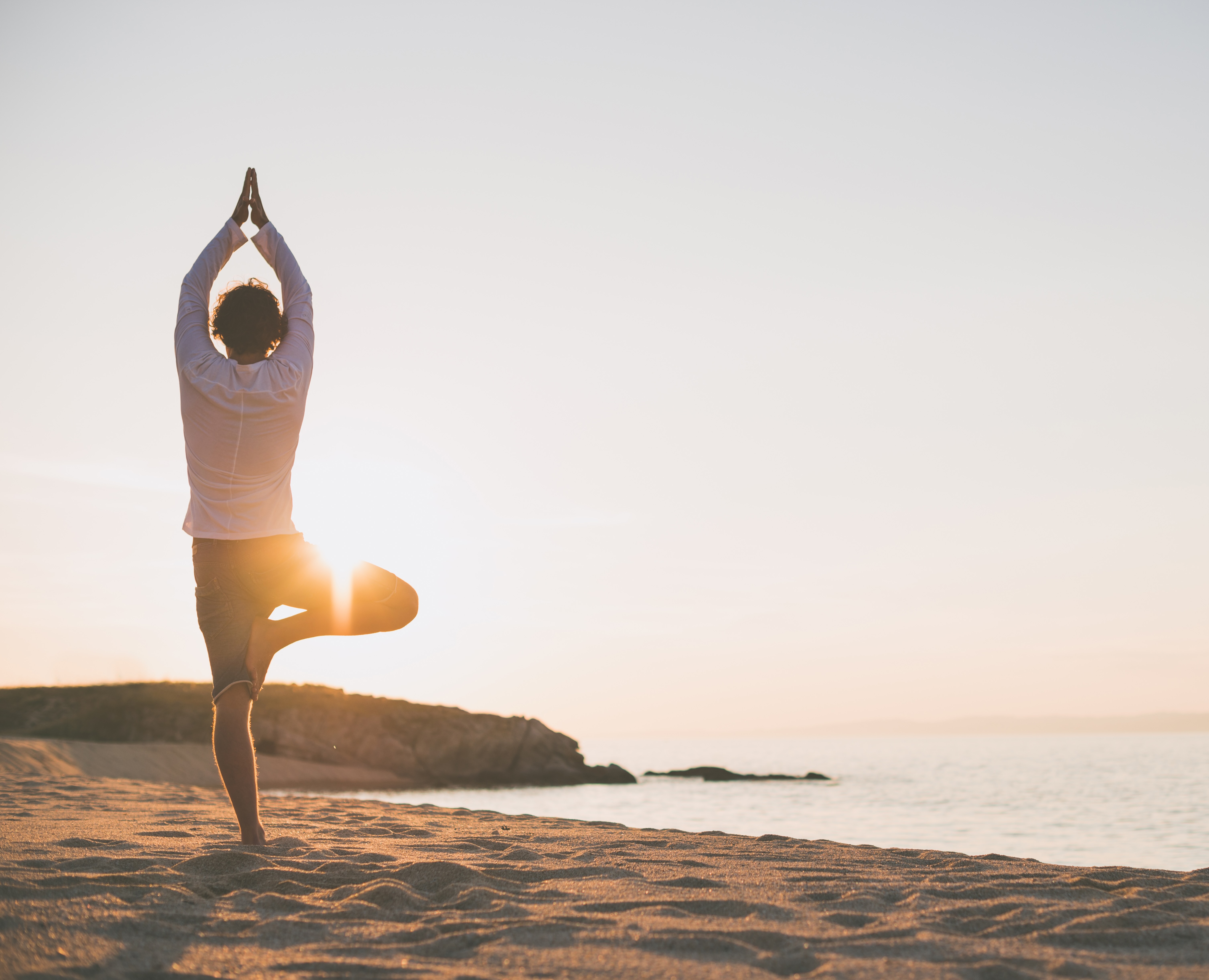 Mann macht Yoga am Strand
