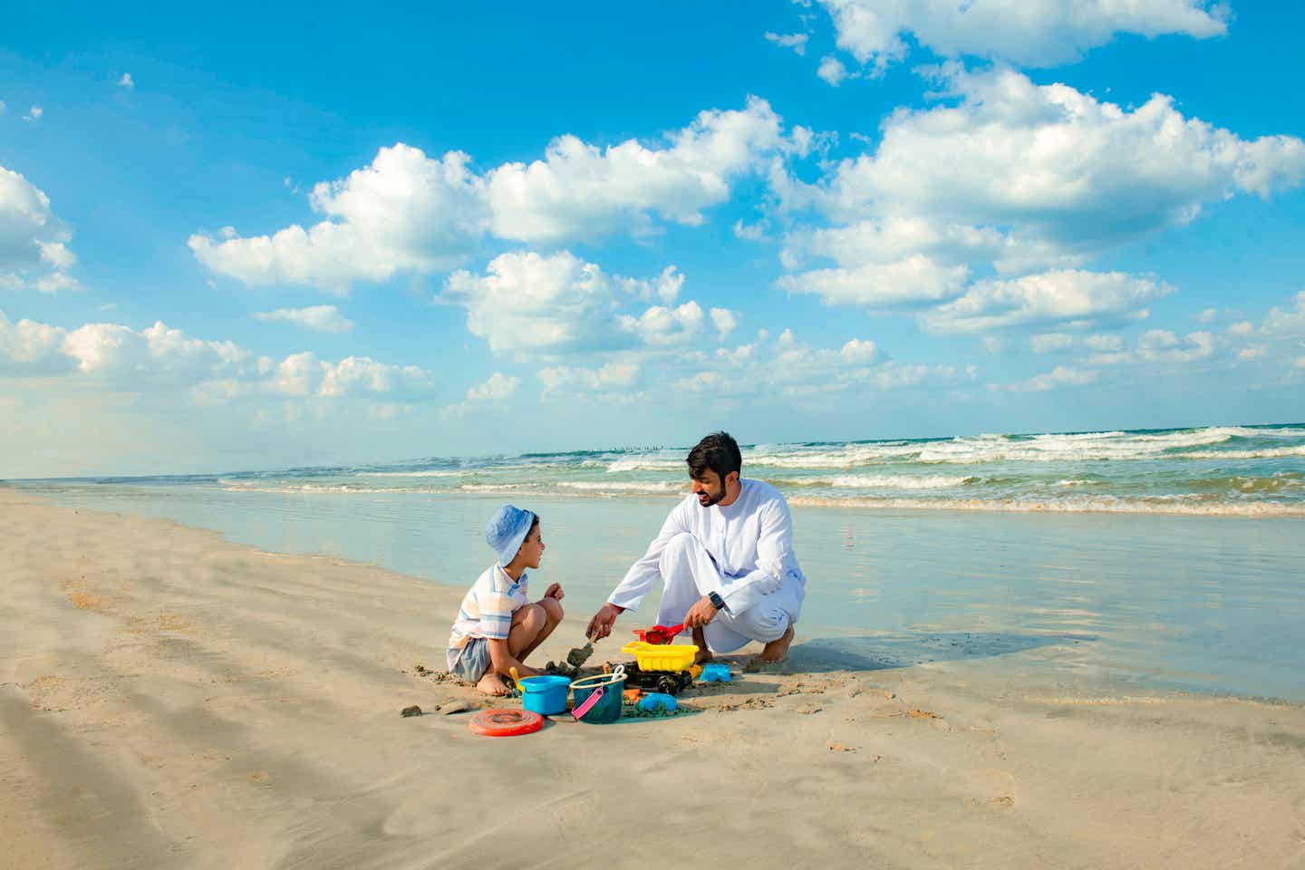 Vater und Sohn spielen am Strand in Ajman