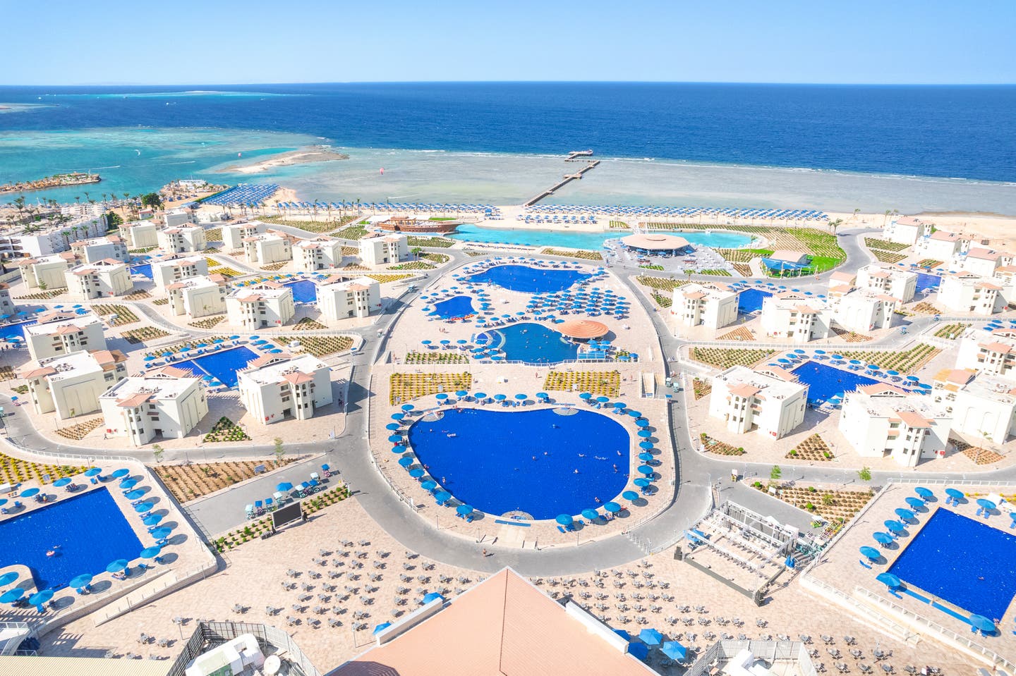 Luftbild des Resorts mit Pools und Unterkünften und dem Strand im Hintergrund