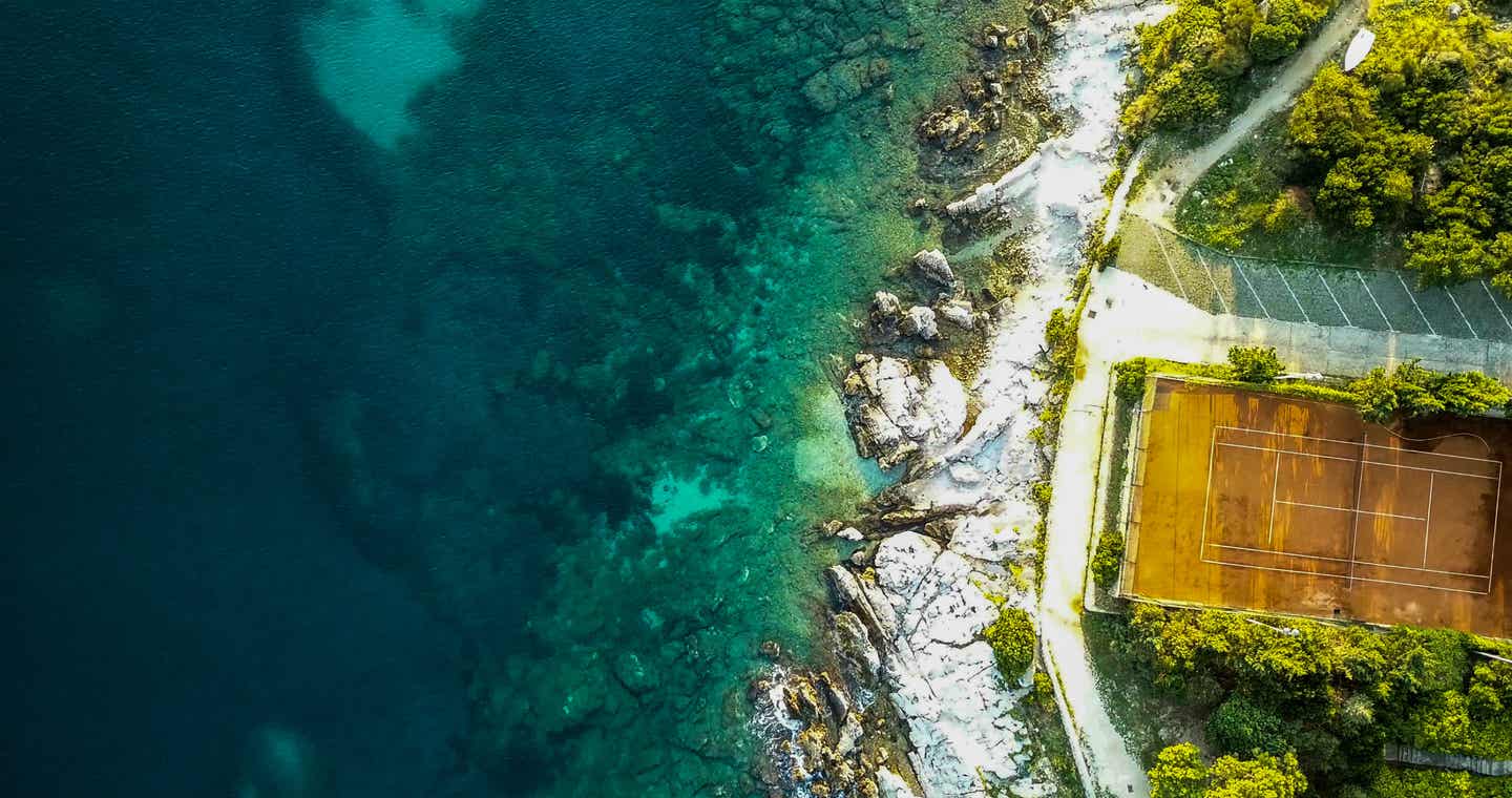 Tolle Kulisse für Tennisspieler: Die Küste vor Dubrovnik von oben mit glasklarem Wasser und tiefrotem Sand