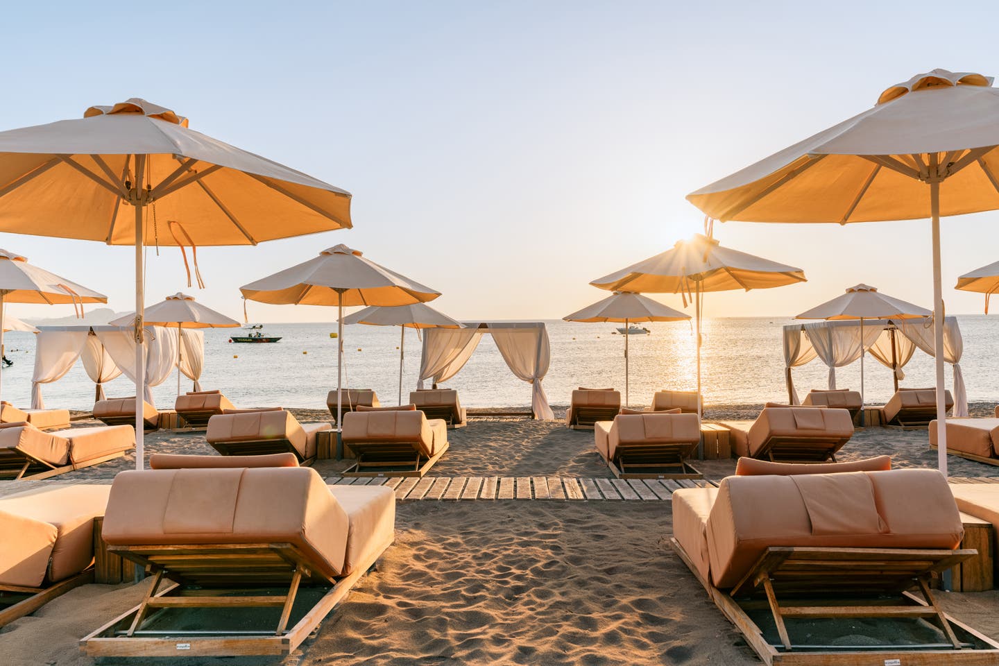 Blick auf den Strand mit Sonnenliegen und untergehender Sonne