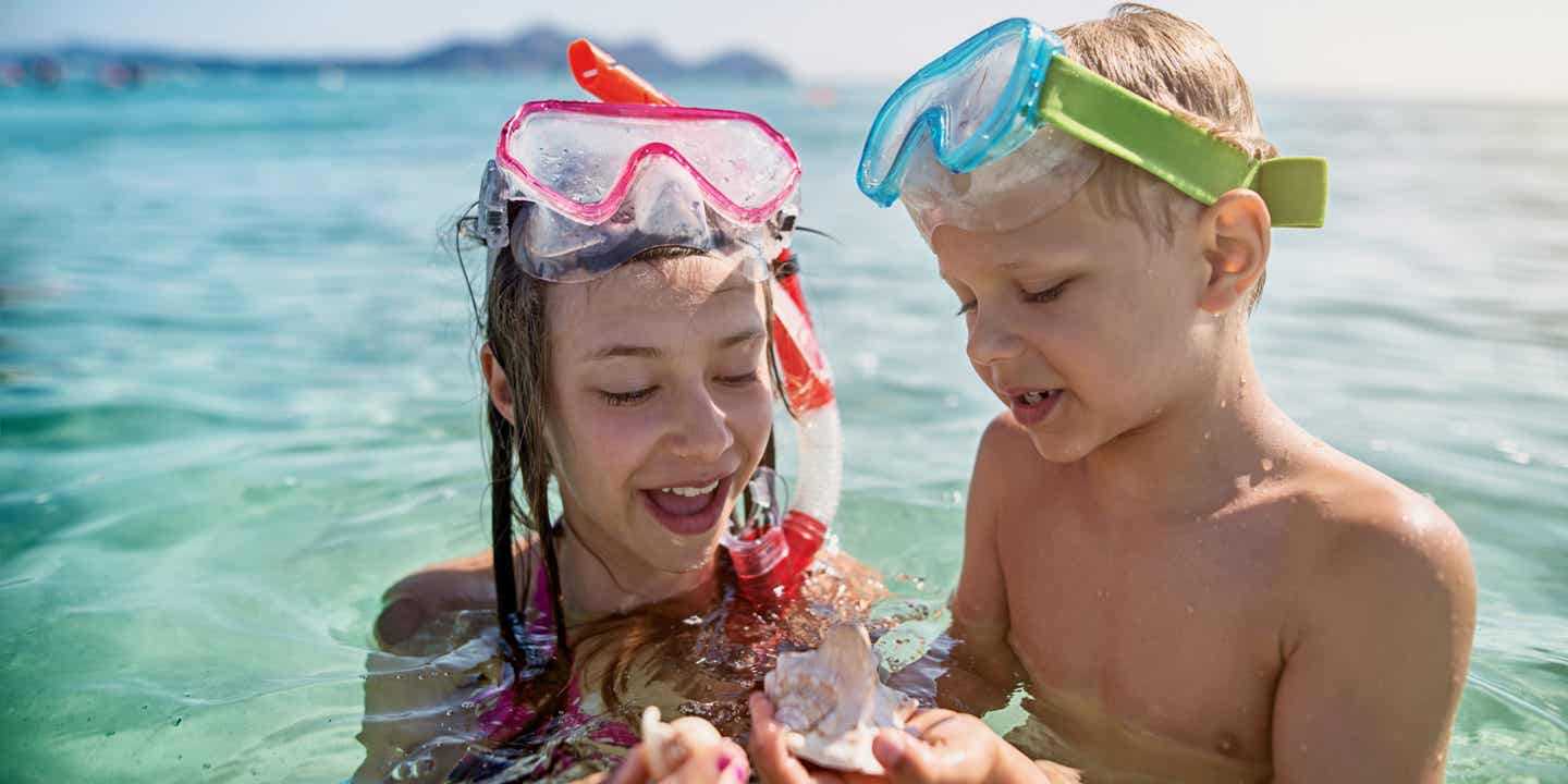 Familienurlaub in Spanien: Junge und Mädchen beim Schnorcheln im klaren Wasser