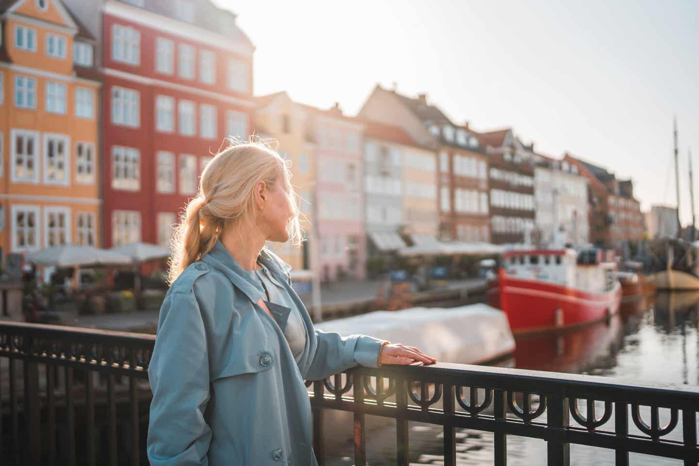 Alleinreisende Frau mit blonden Haaren schaut auf Fluss in Kopenhagen
