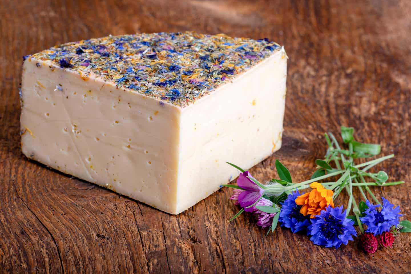 Sehenswürdigkeiten im Allgäu: Bergkäse mit Blumen auf Holz