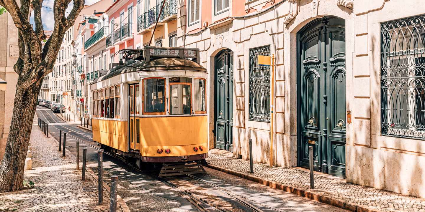 Die historische Tram 28E fährt durch eine enge Gasse in Lissabon