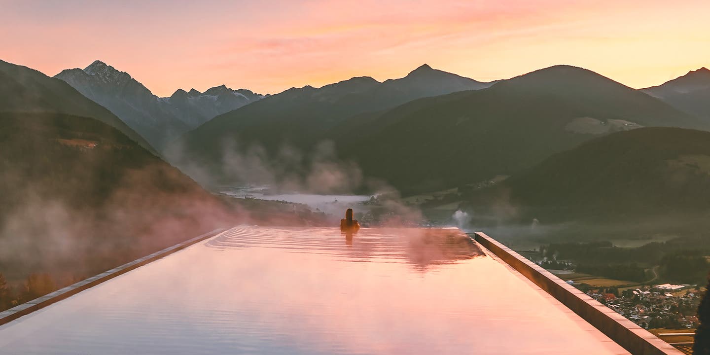 Frau vor Sonnenuntergang im Infinity-Pool in Südtirol