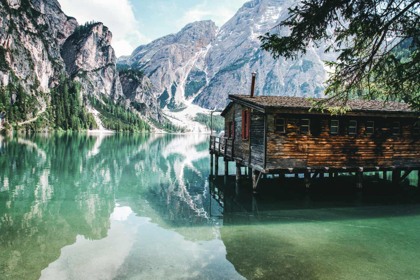 Südtirol Urlaub mit DERTOUR. Pragser Wildsee mit Bootshaus und den Pragser Dolomiten im Hintergrund