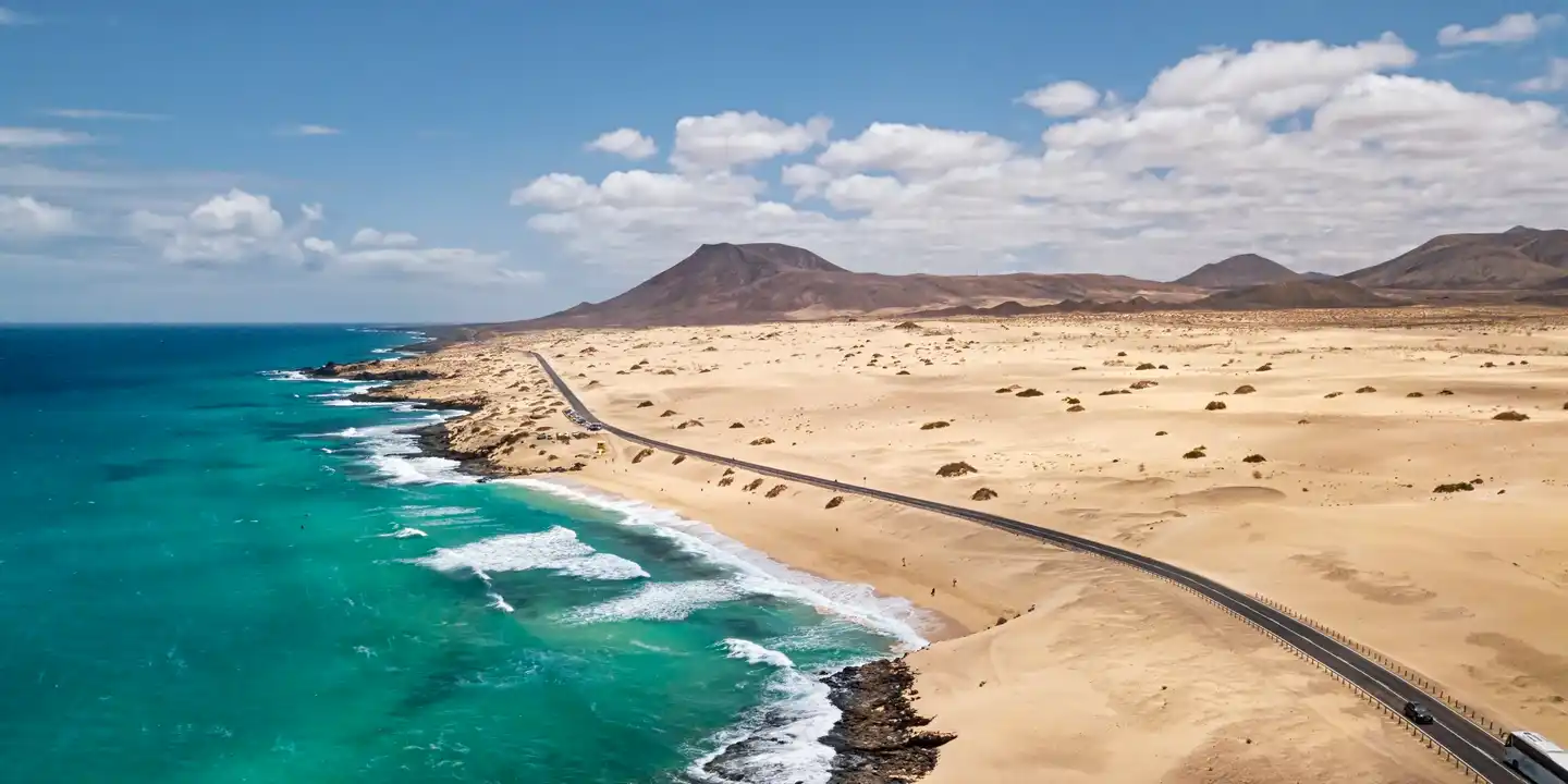 Küstenstraße im Corralejo Naturpark auf Fuerteventura mit Sandlandschaft, Atlantik und türkisblauem Wasser