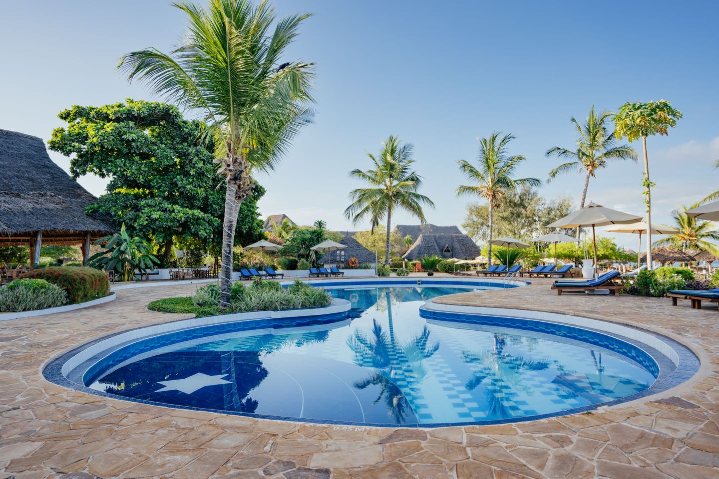 Pool mit Sonnenliegen inmitten des Hotels