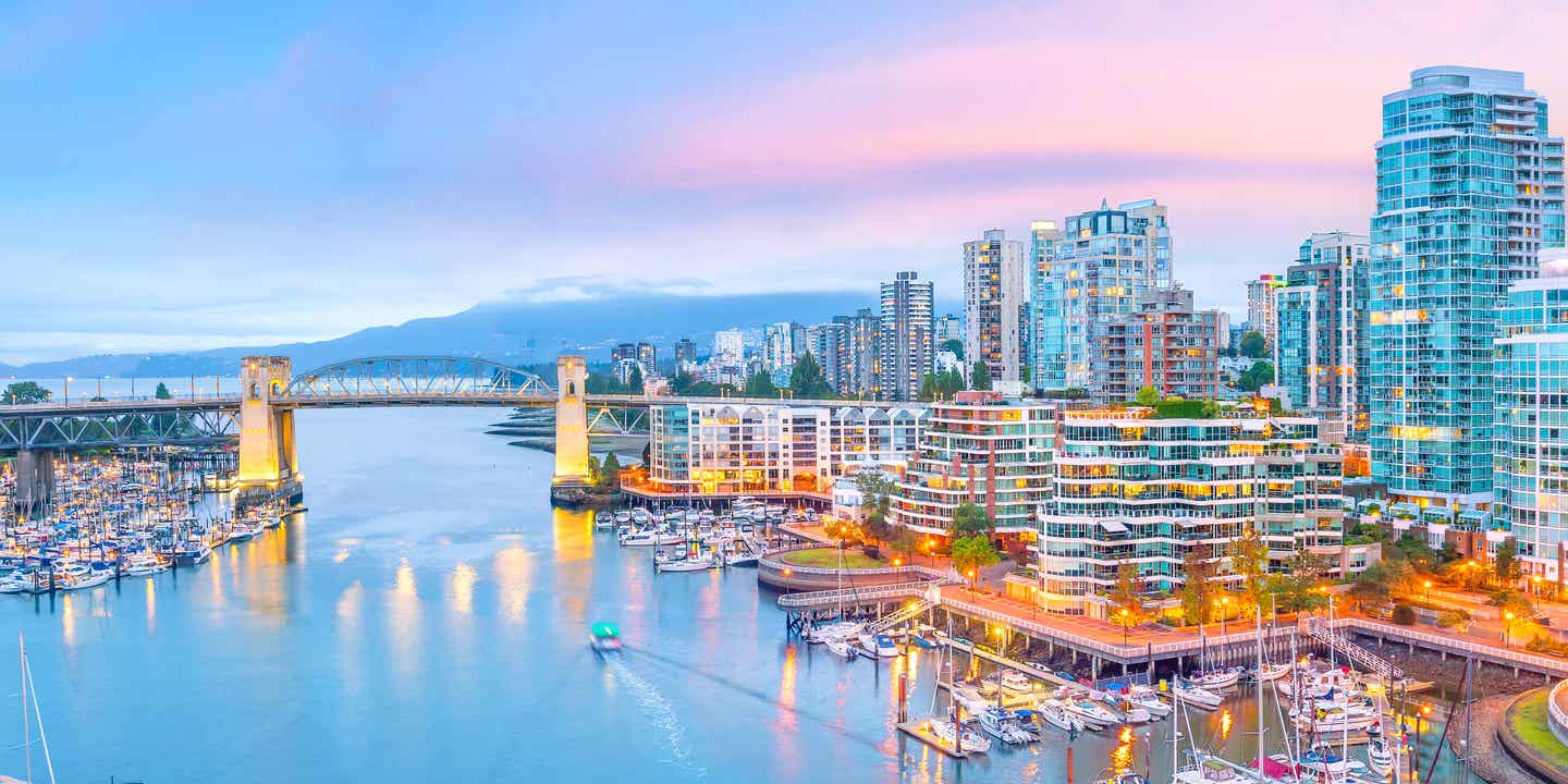 Blick auf die Skyline von Vancouver mit Yachthafen und Brücke bei Sonnenuntergang in British Columbia, Kanada  