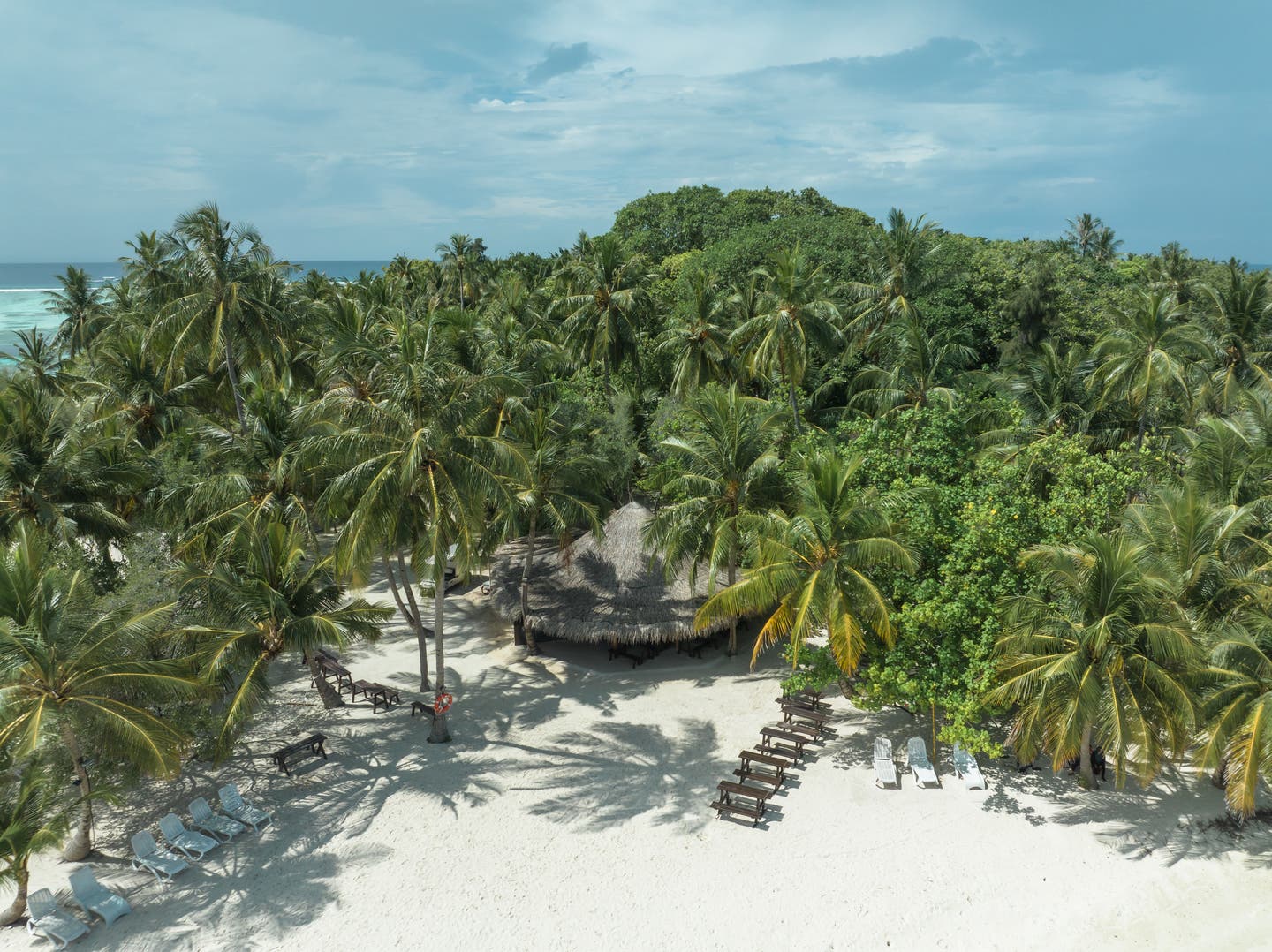 Strand von oben mit Palmen und Wasserbungalows