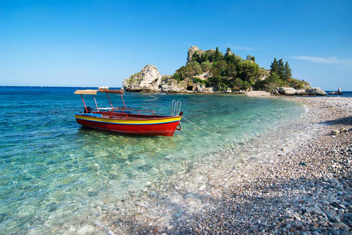 Reiseziel Oktober: Rotes Boot auf dem Wasser an Siziliens Isola Bella