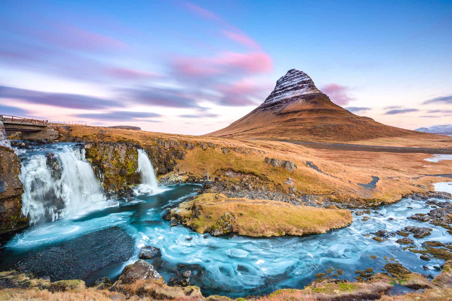 Bläulich schimmernder Wasserfall vor einem markanten Berg – der Kirkjufellsfoss auf Island.