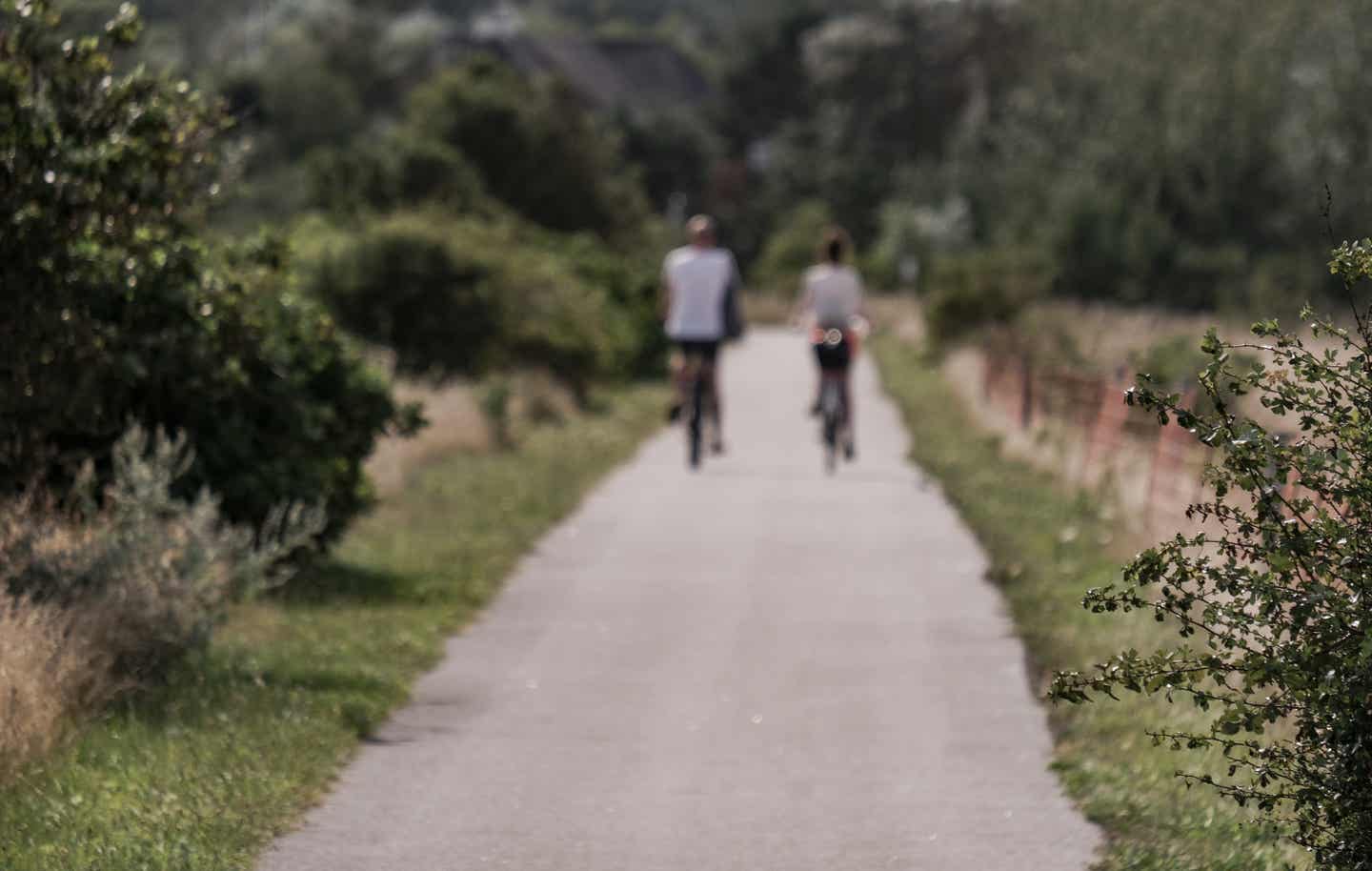 Schleswig Holstein Urlaub mit DERTOUR. Unscharfe Aufnahme eines Paares beim Radfahren auf Sylt