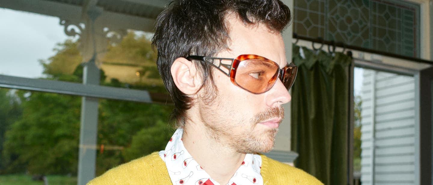 Promobild von Harry Styles, auf dem er einen leuchtend gelben Pulli und eine rote Krawatte trägt